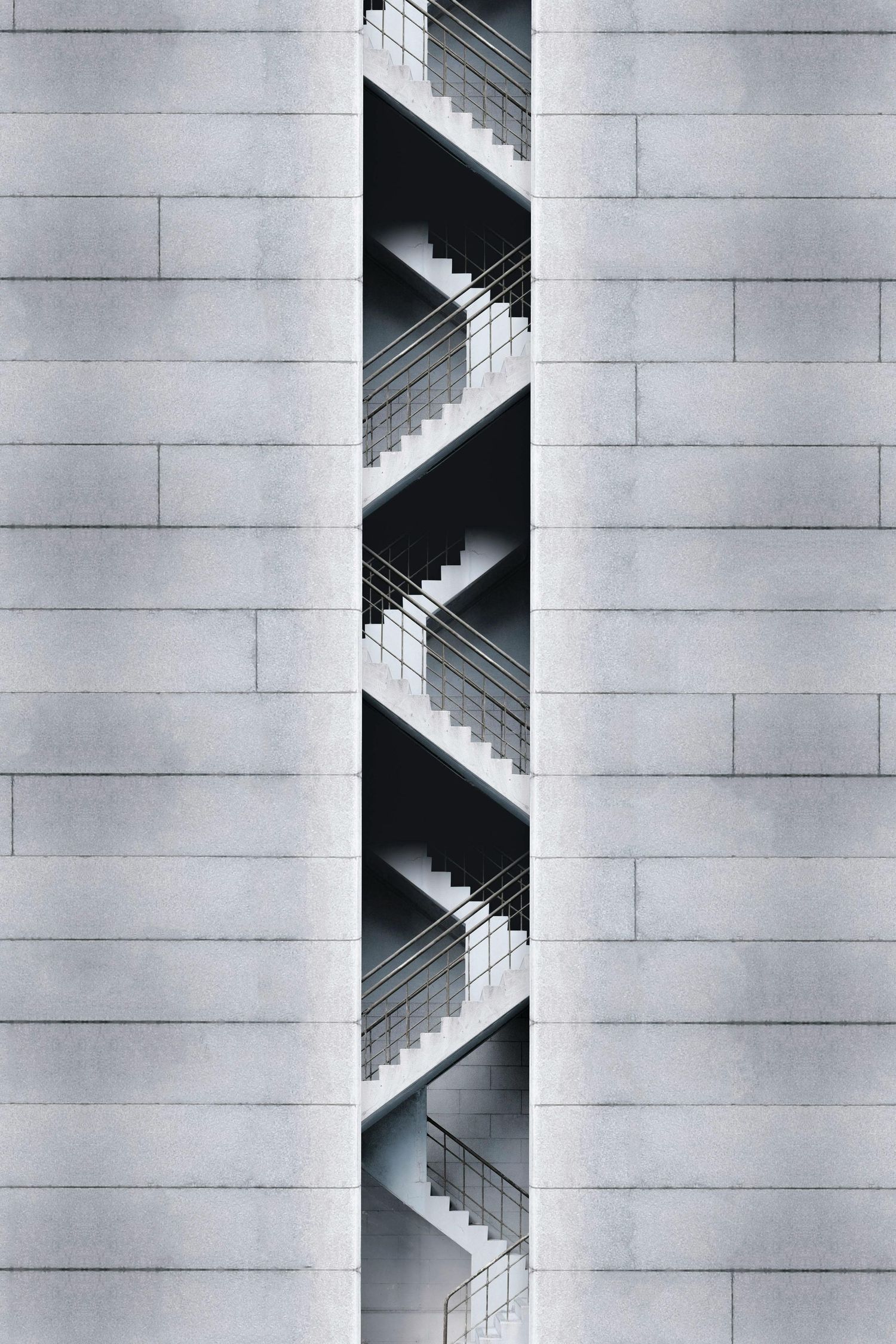 Minimalist architectural photo of zigzagging staircase against concrete wall.