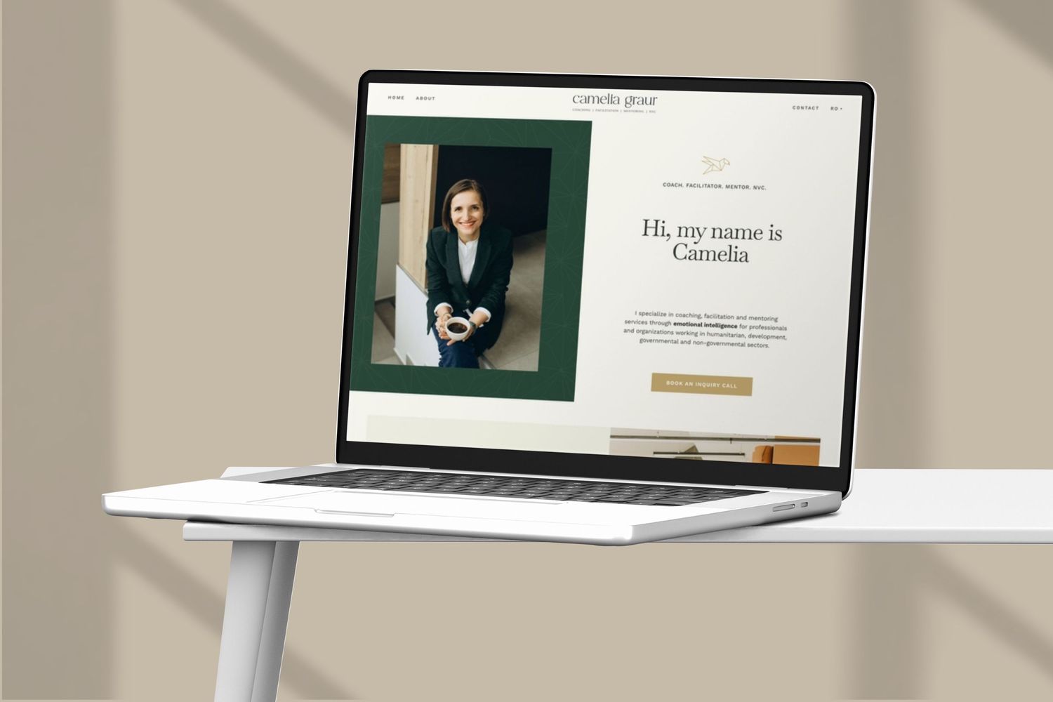 A laptop displaying a professional website homepage with dark green accents sits on a white desk.