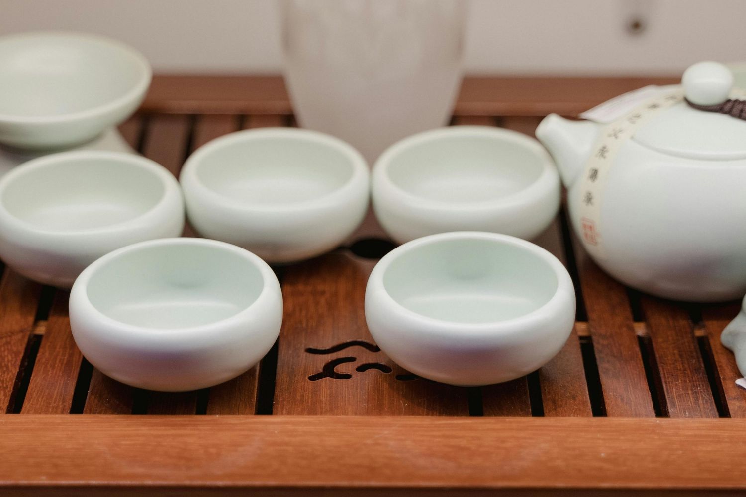 White ceramic tea cups arranged on wooden tea tray in minimalist style.