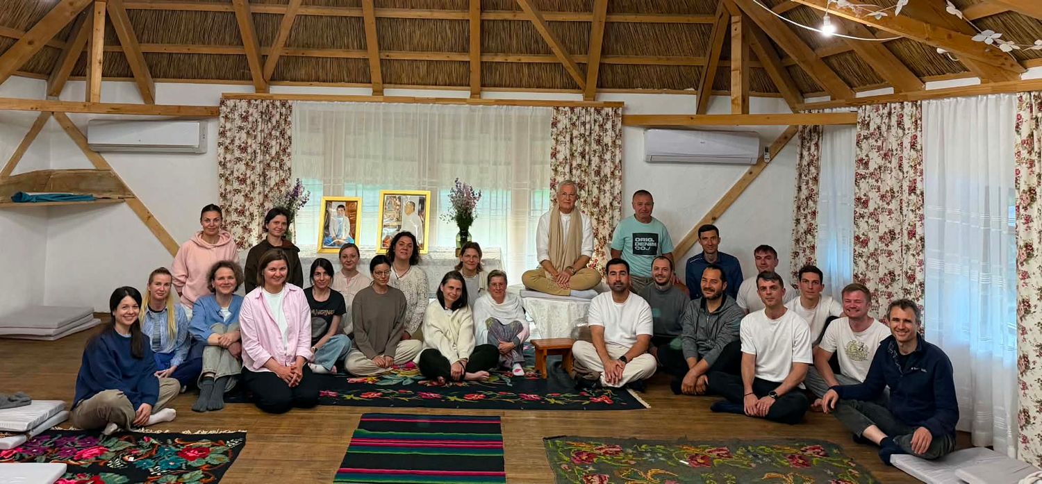 Group of diverse people sitting together in a rustic thatched-roof yoga or meditation studio for a retreat.