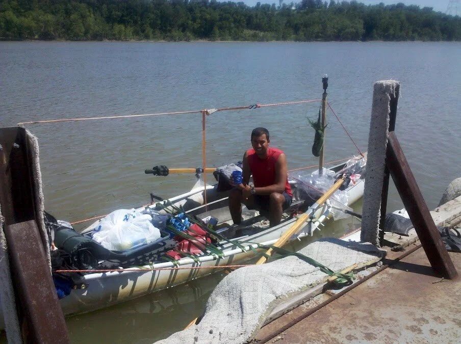 Long boats loaded with supplies docked at a riverside pier.