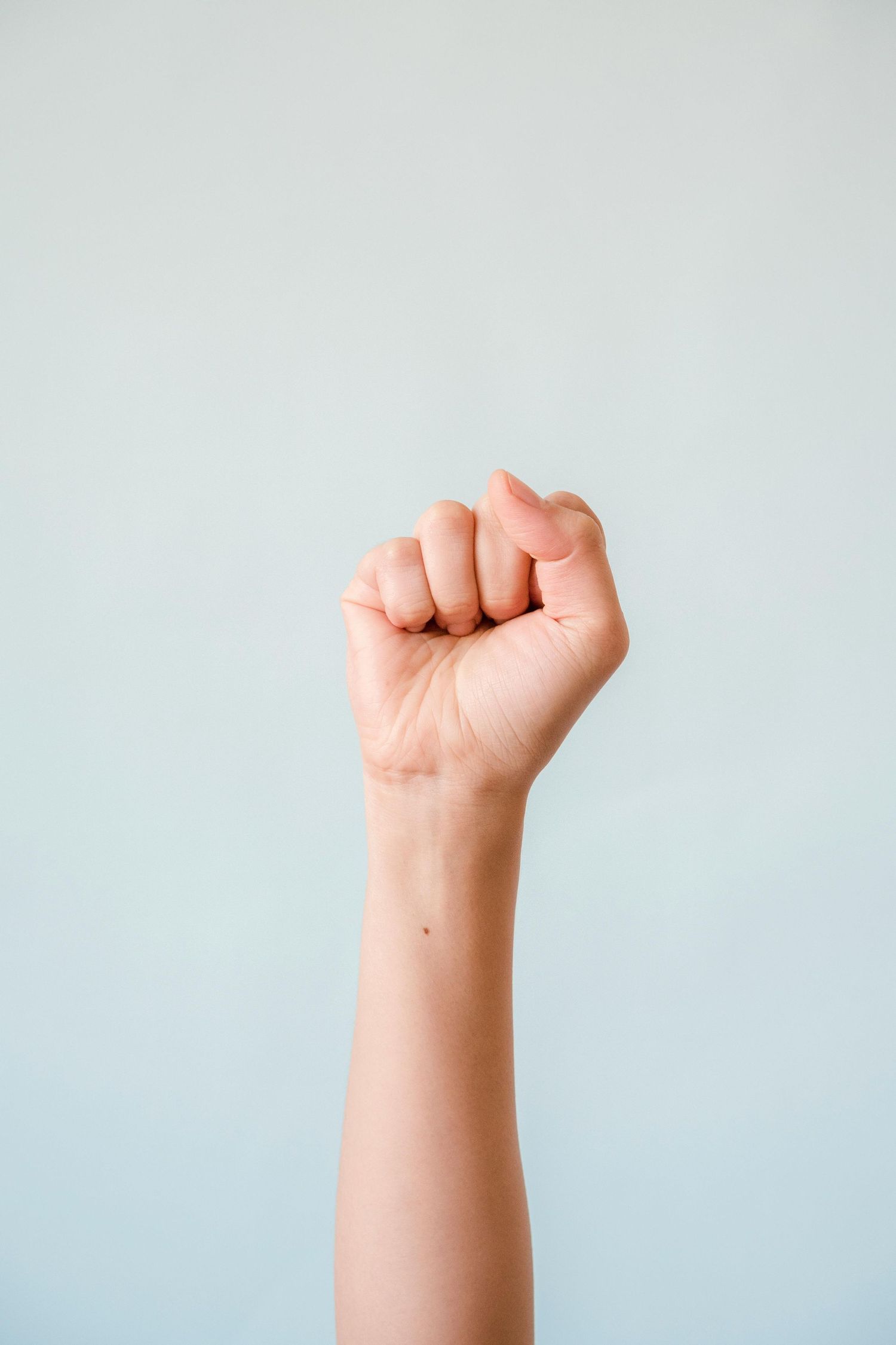 Series of raised fists against a light gray background showing strength and solidarity.