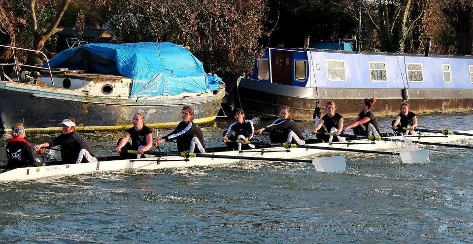Competitive rowing scene showing multiple boats racing across water.
