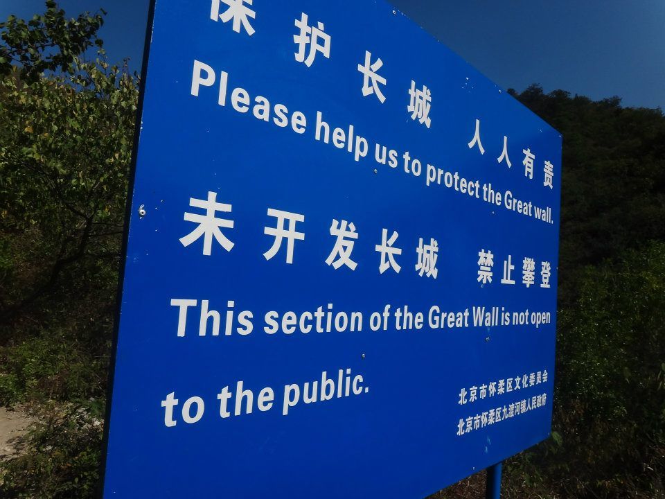 Blue warning sign in Chinese and English about an unopened section of the Great Wall not being open to the public.