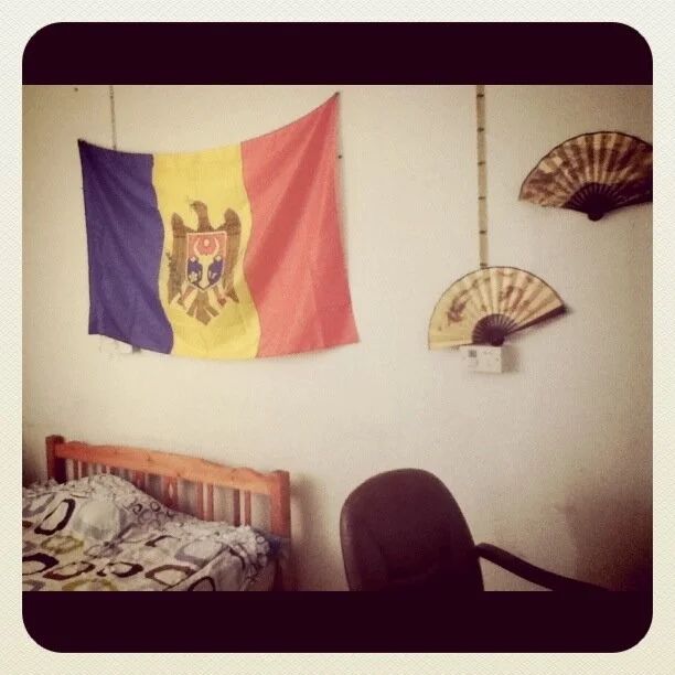 Room interior with flags and decorative fans hanging on white walls.
