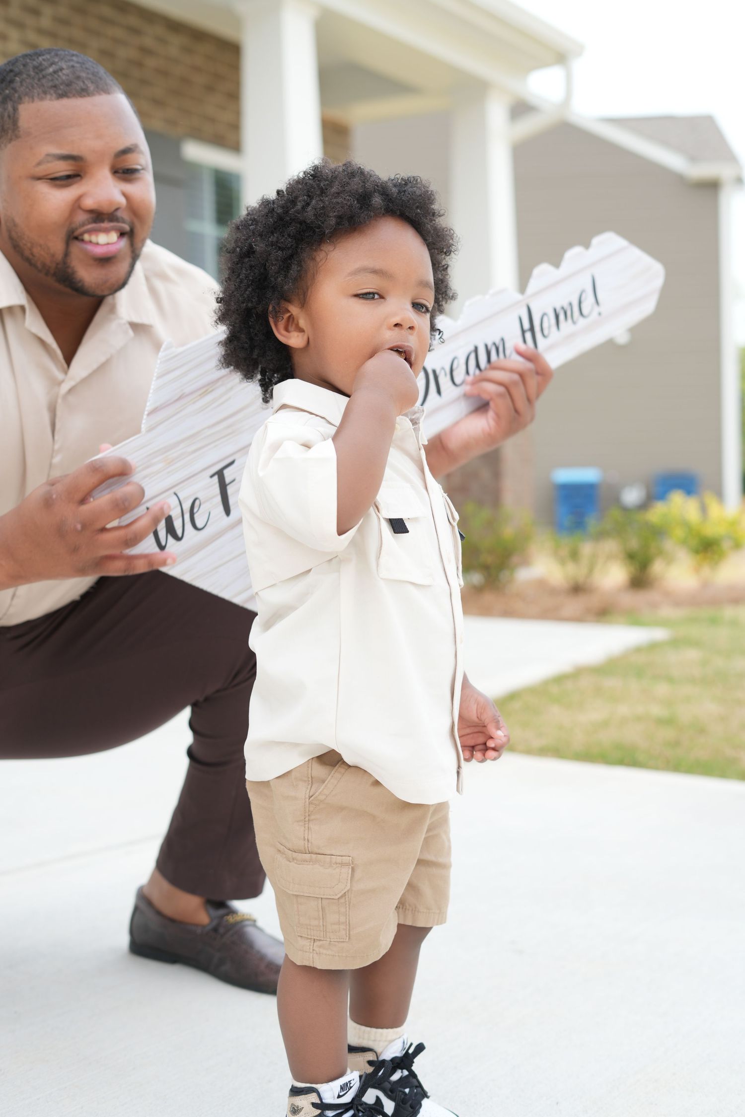 A child and adult holding welcome signs on their front porch.