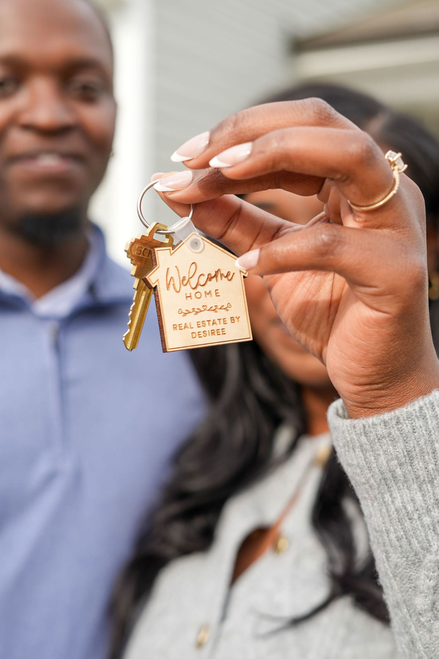 Close-up of hands holding house keys with wooden keychain.