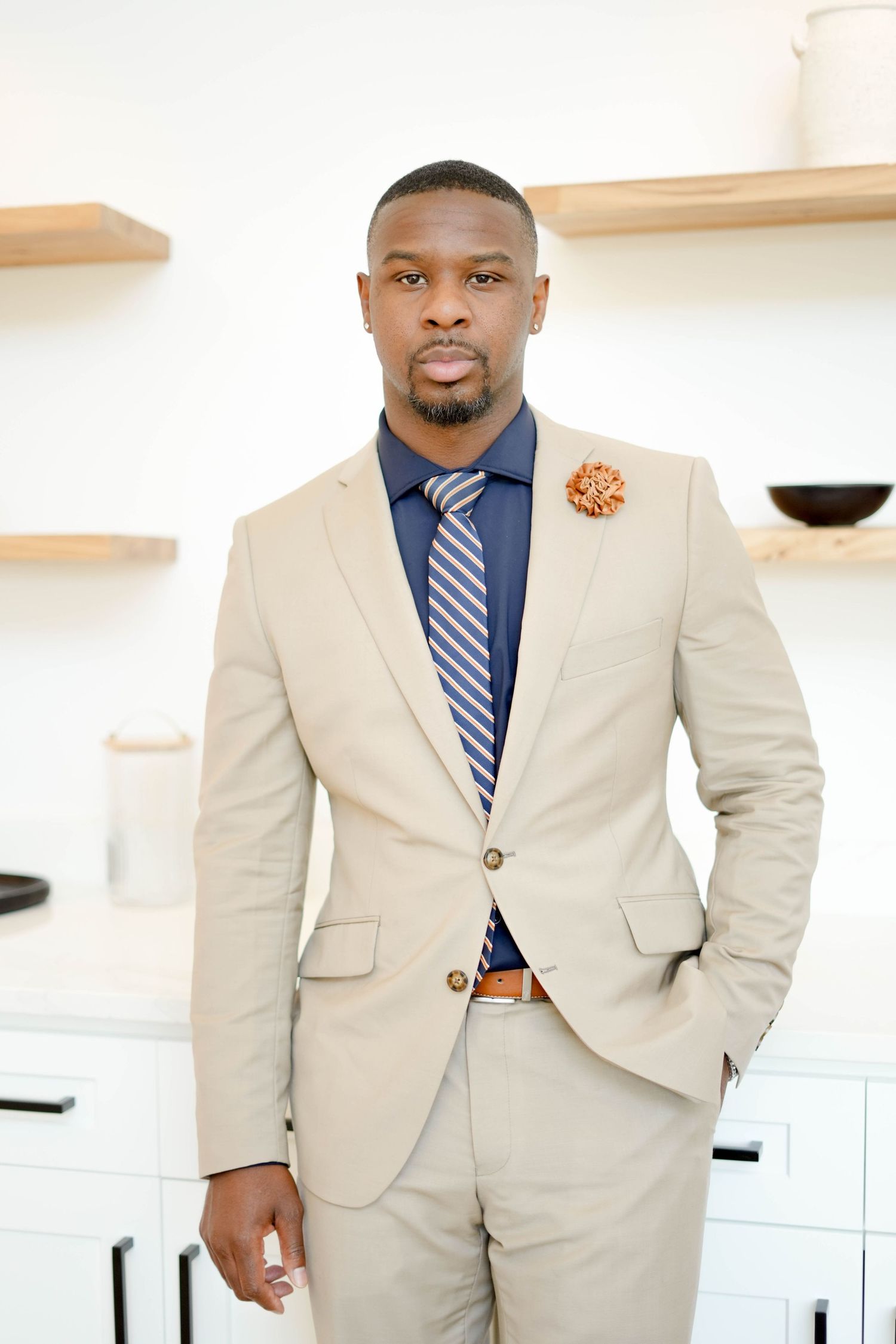 Businessman in beige suit and blue tie standing in modern office.