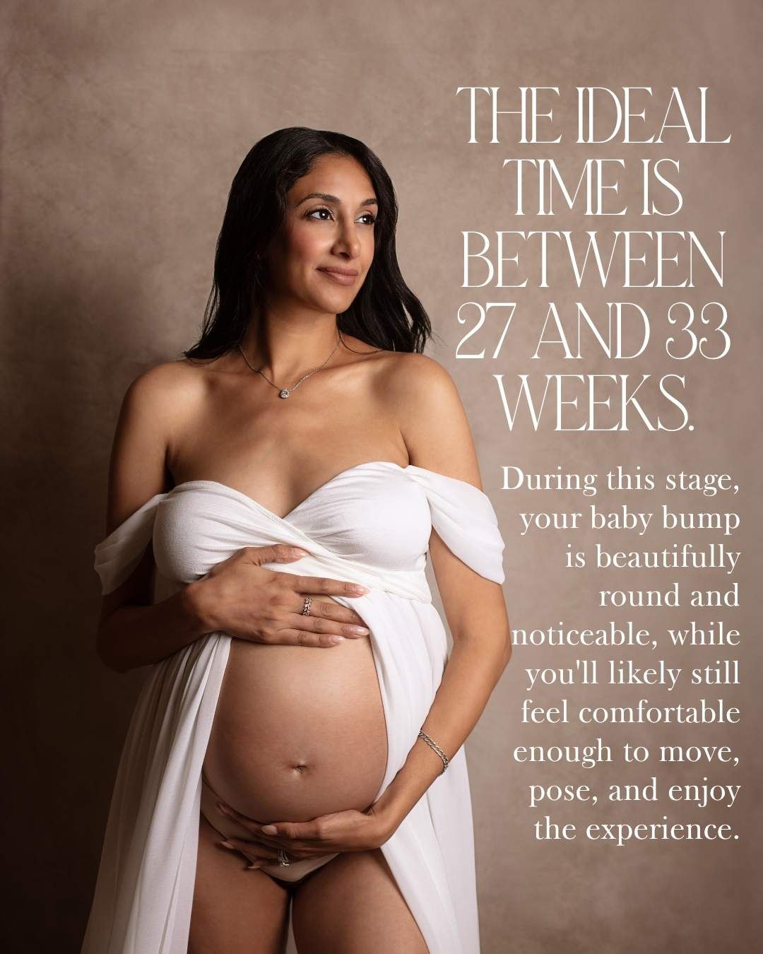 Pregnant woman in white draped fabric at 27-33 weeks maternity photoshoot, showcasing a beautifully round baby bump.