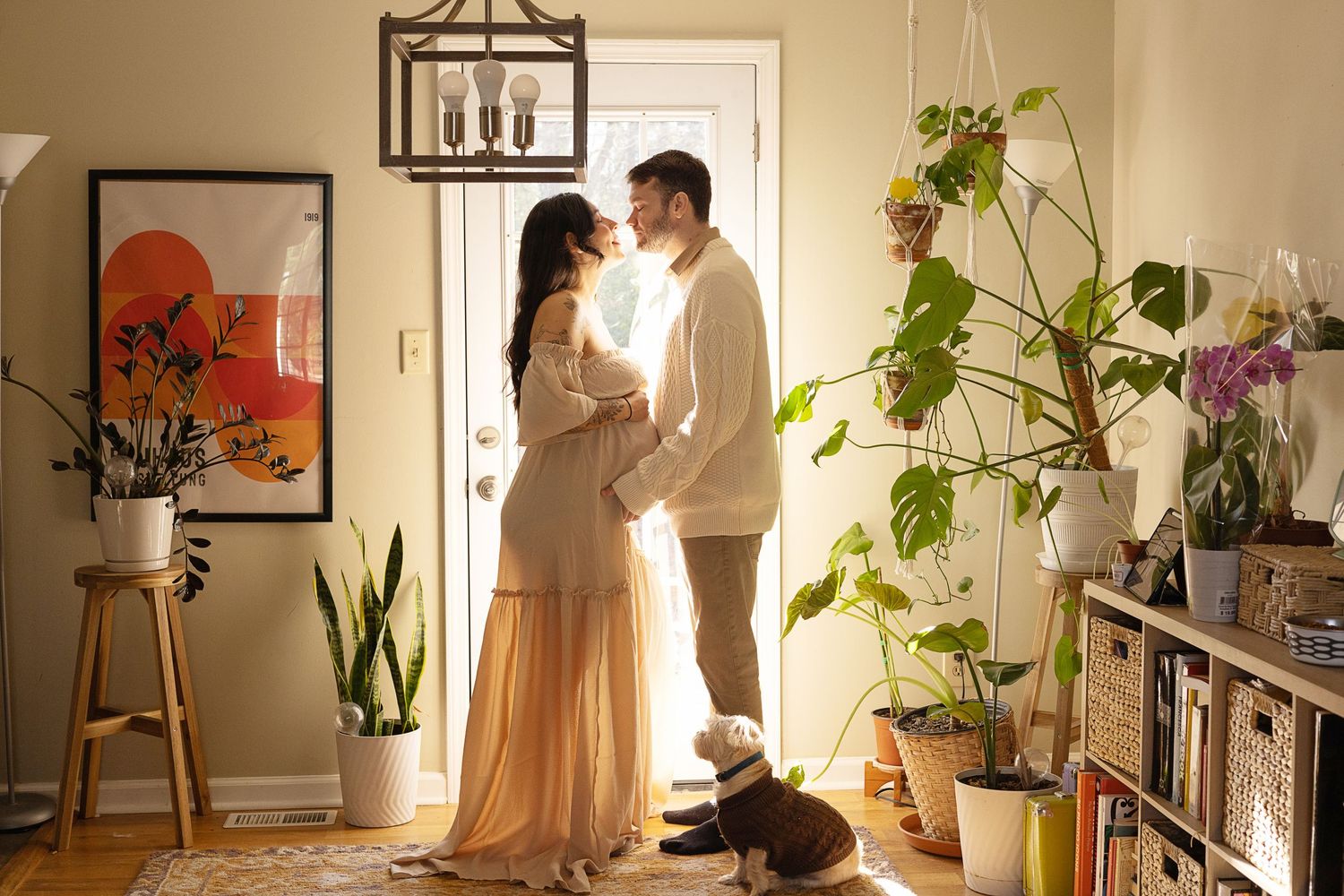 Couple sharing a romantic moment in a cozy plant-filled apartment entryway with a small dog sitting nearby.