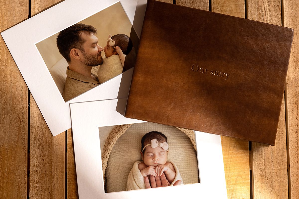Newborn photos with leather keepsake box, featuring a dad holding baby and sleeping newborn girl with pink bow.