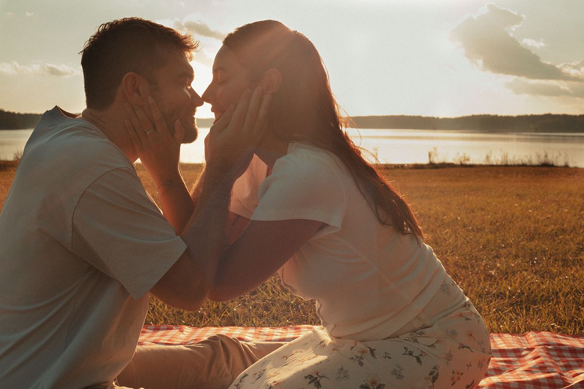 Romantic couple sharing a tender moment at sunset by a lake during a golden hour photoshoot in Douglasville, Georgia