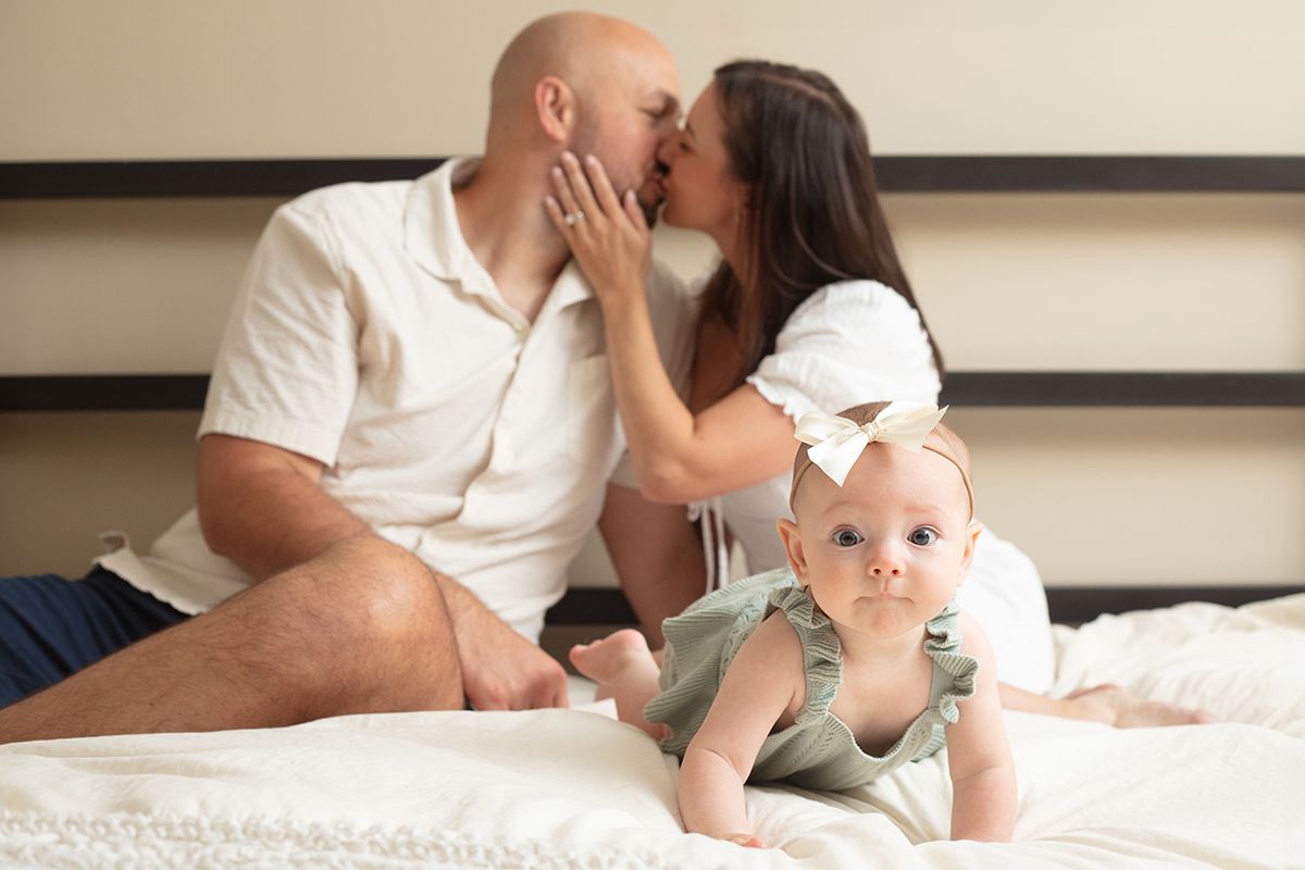 family sitting together on a white bed during an in-home family photoshoot in Atlanta, Georgia