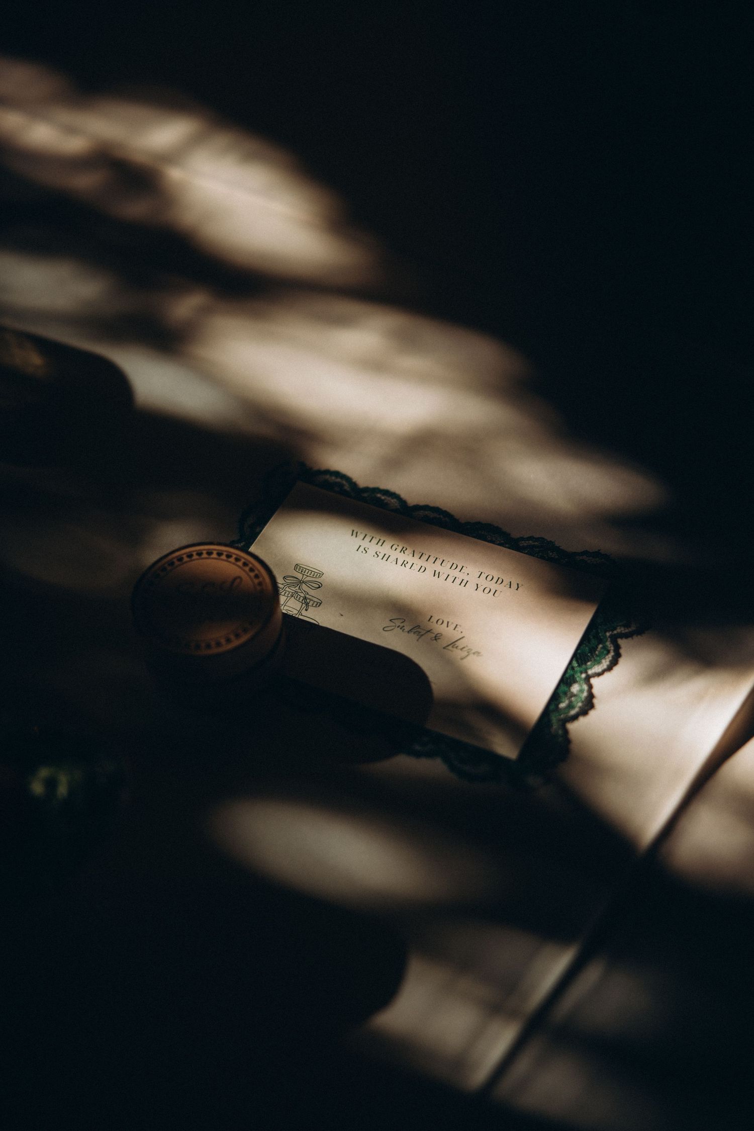 Romantic wedding vow scroll with wax seal resting in dramatic shadow light.