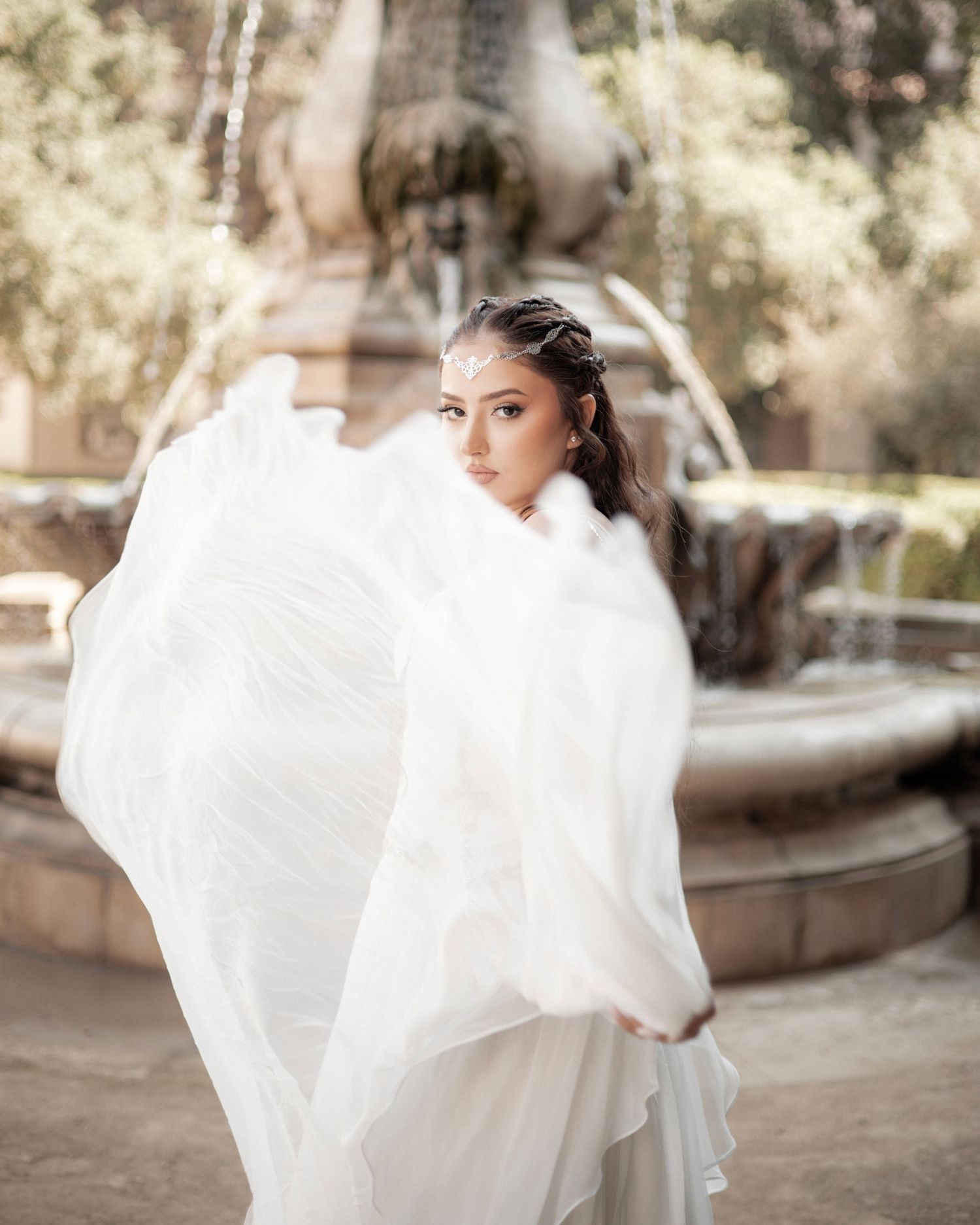 Flowing white wedding dress captured in motion against natural outdoor setting.