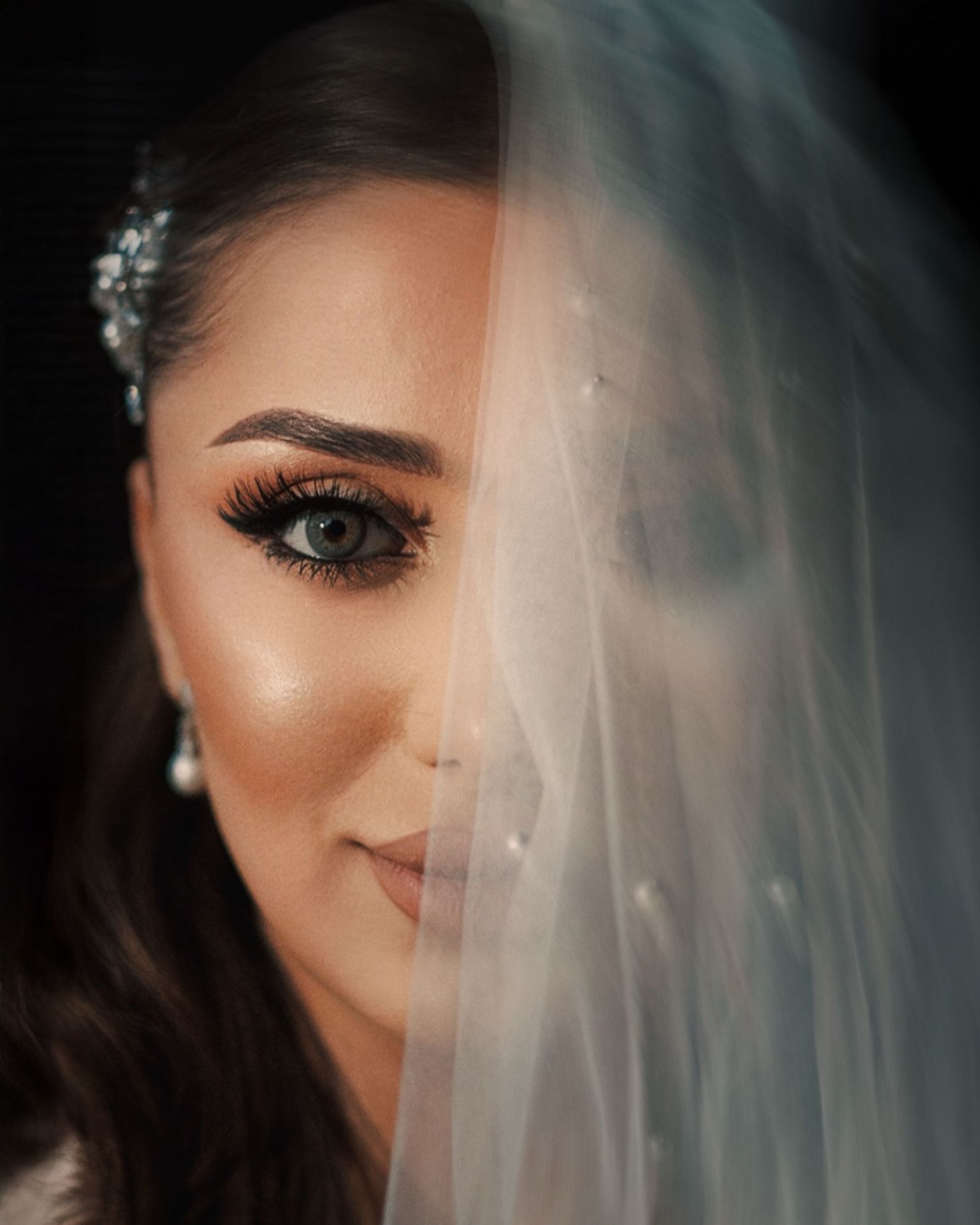 Close-up bridal portrait with delicate veil and glamorous makeup.