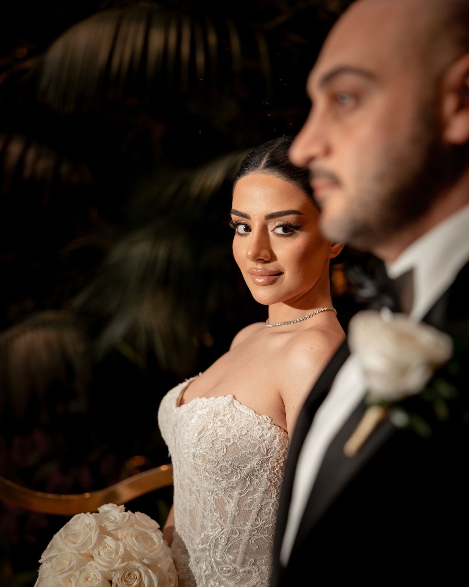 An elegant wedding portrait featuring a couple in formal attire with the bride in a strapless lace gown.
