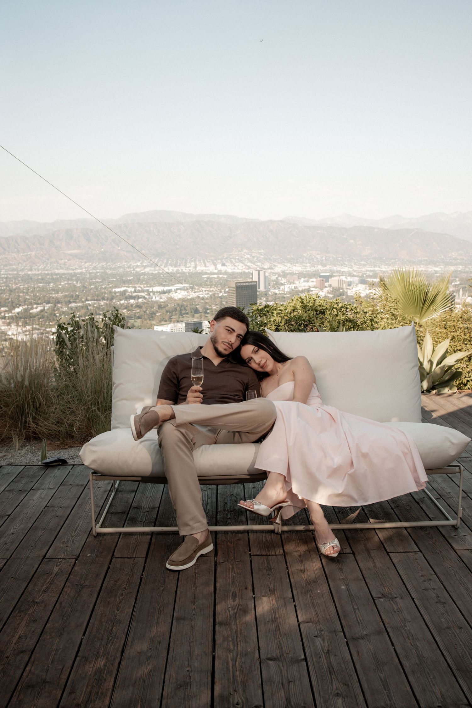 Couple relaxing on outdoor deck with cityscape view.