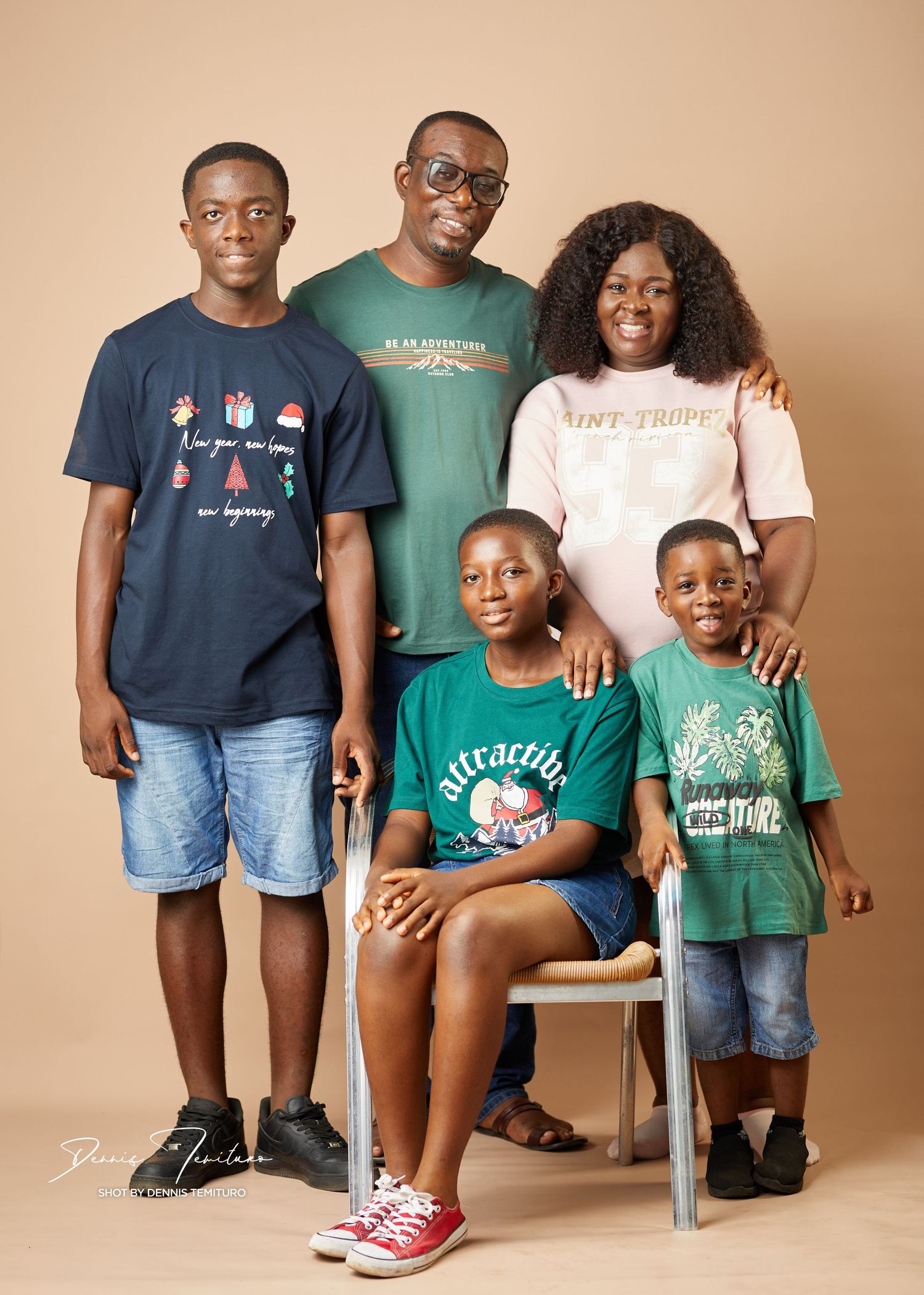 Studio portrait of a family in casual clothing against a beige background.