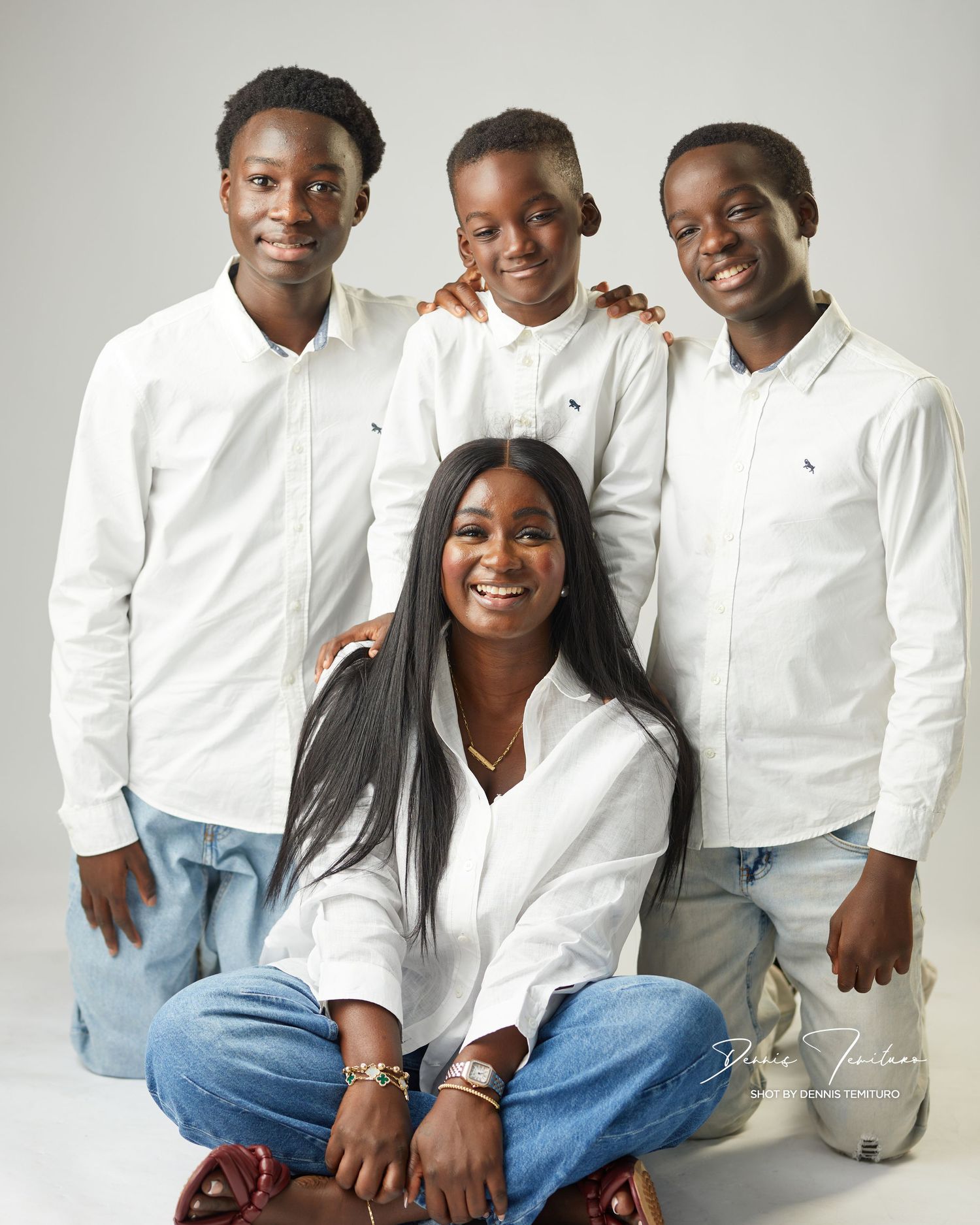 Studio portrait of four people in matching white shirts and jeans.