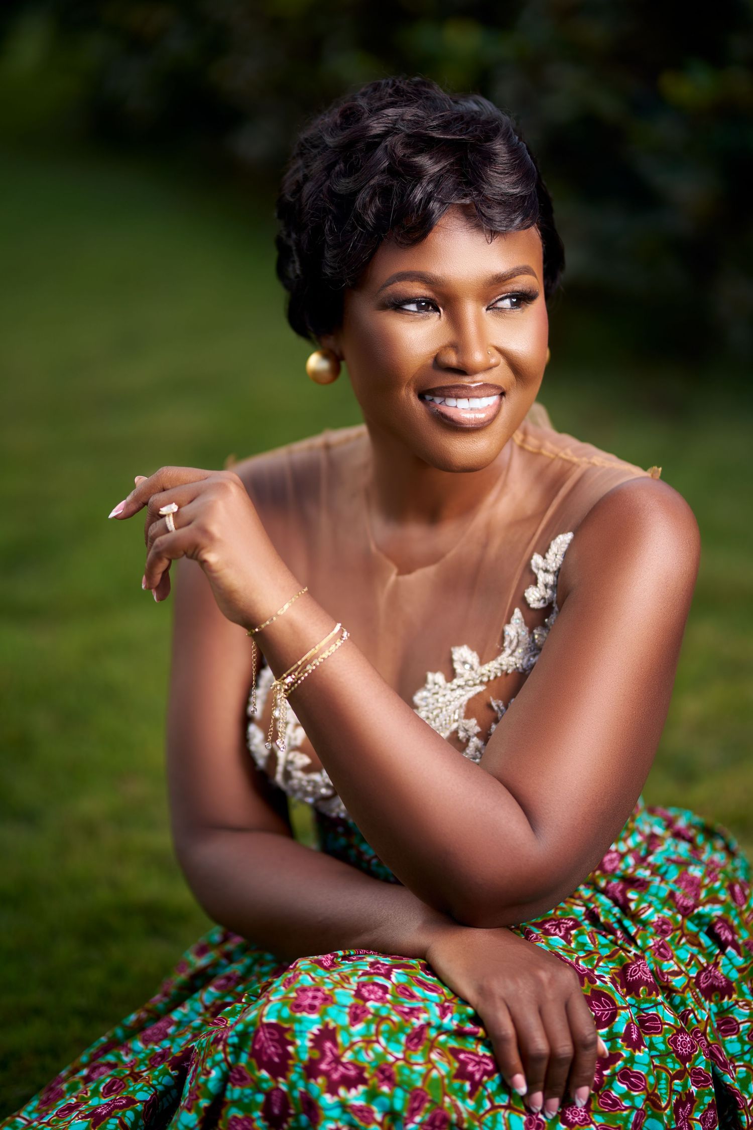 Glamour photoshoot featuring a floral print dress and jewelry in an outdoor garden setting.