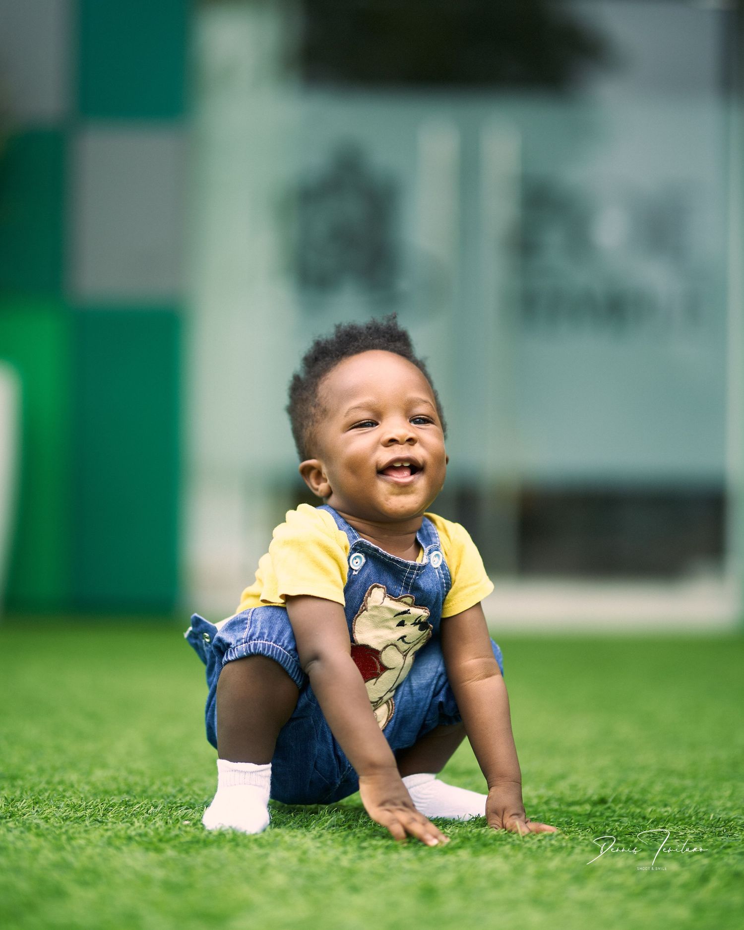 Crawling and playing sequence on green grass wearing yellow shirt and blue shorts.