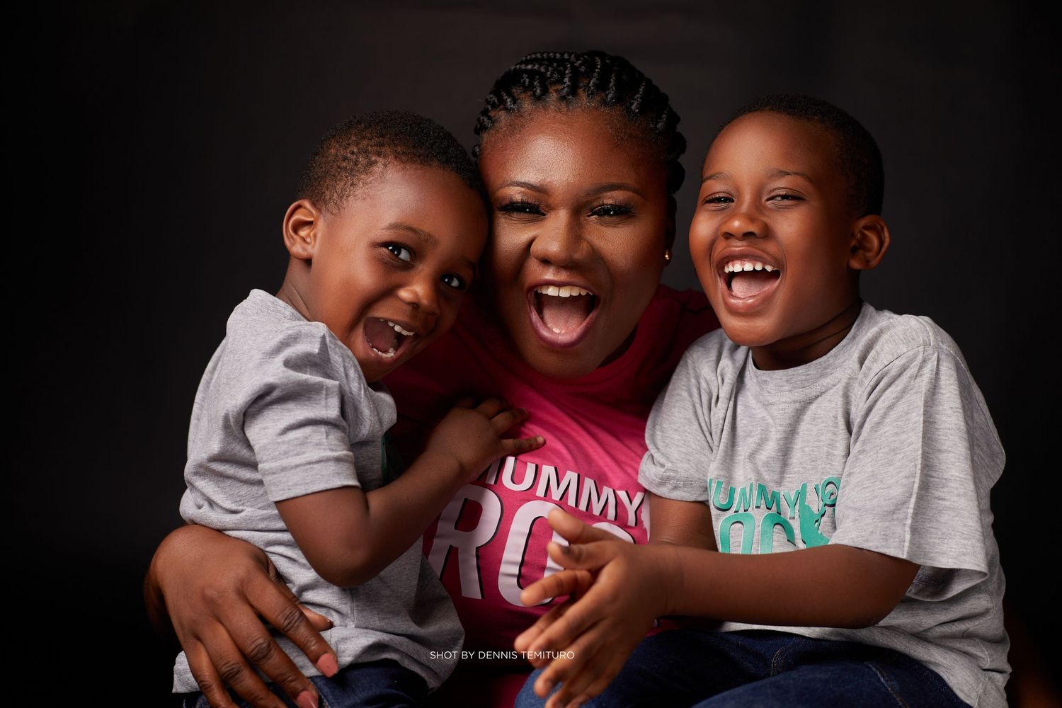 Three people sharing joyful laughter during a dark background photo session.