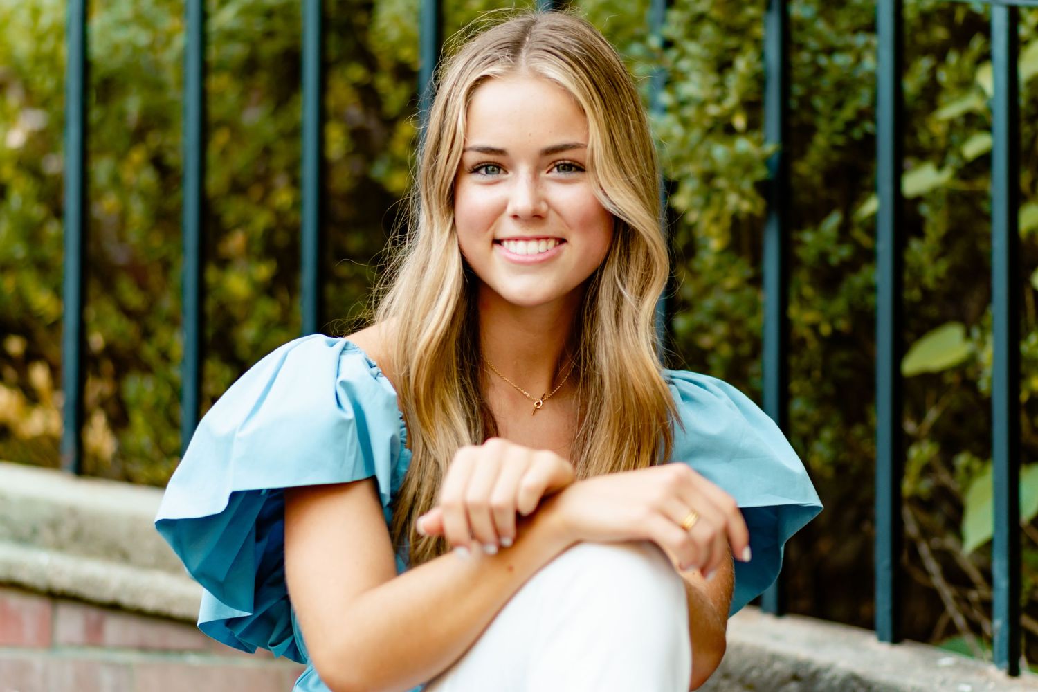 A series of outdoor portraits showing a person in turquoise attire against lush garden greenery and iron fencing.