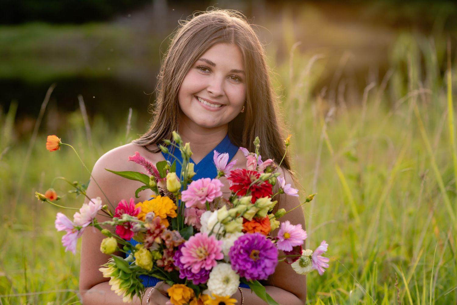 A bright wildflower bouquet sits in a field of tall grass with orange butterflies fluttering nearby on a sunny day.