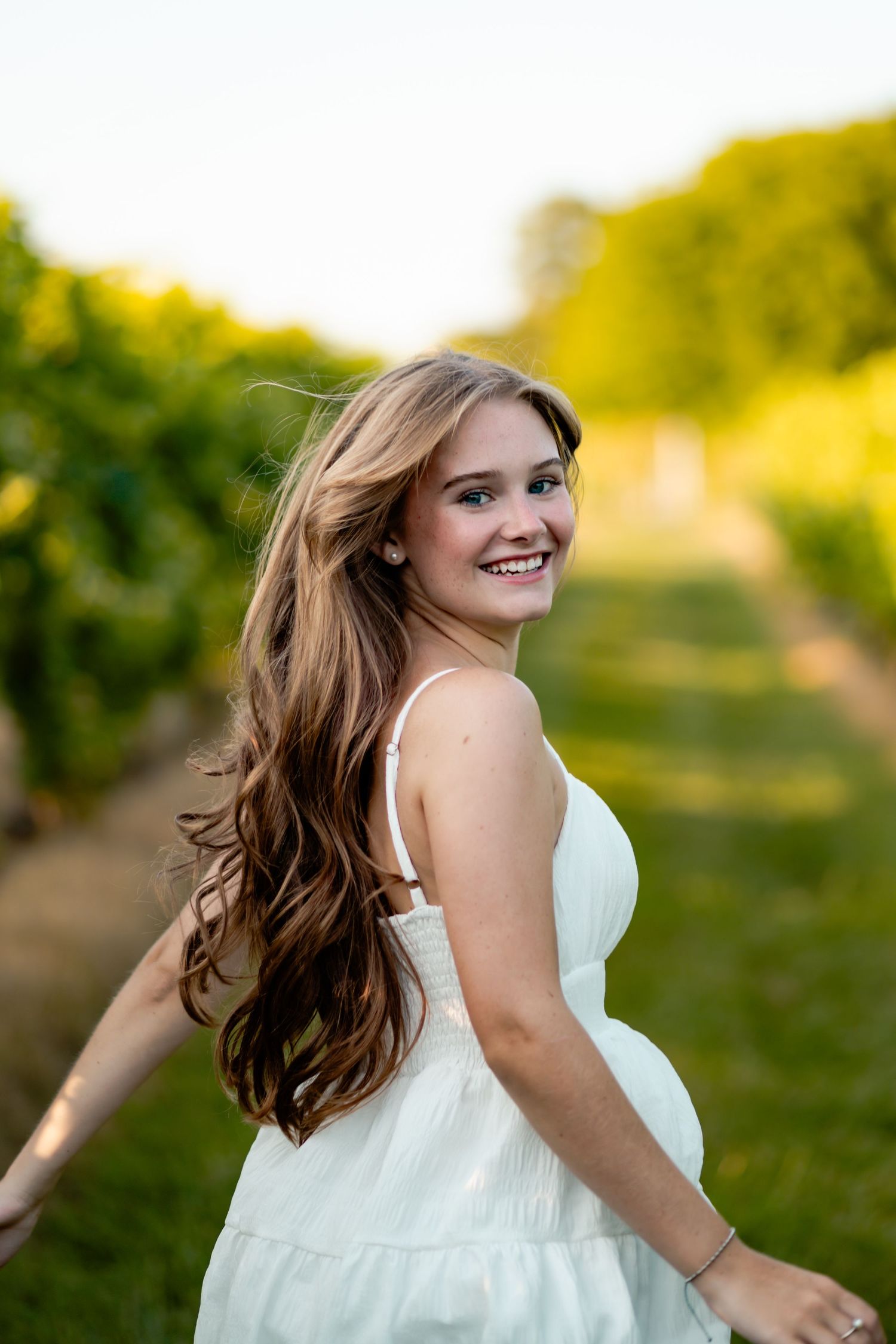 A white sundress twirls against a golden sunset background in a flowing summer portrait series.