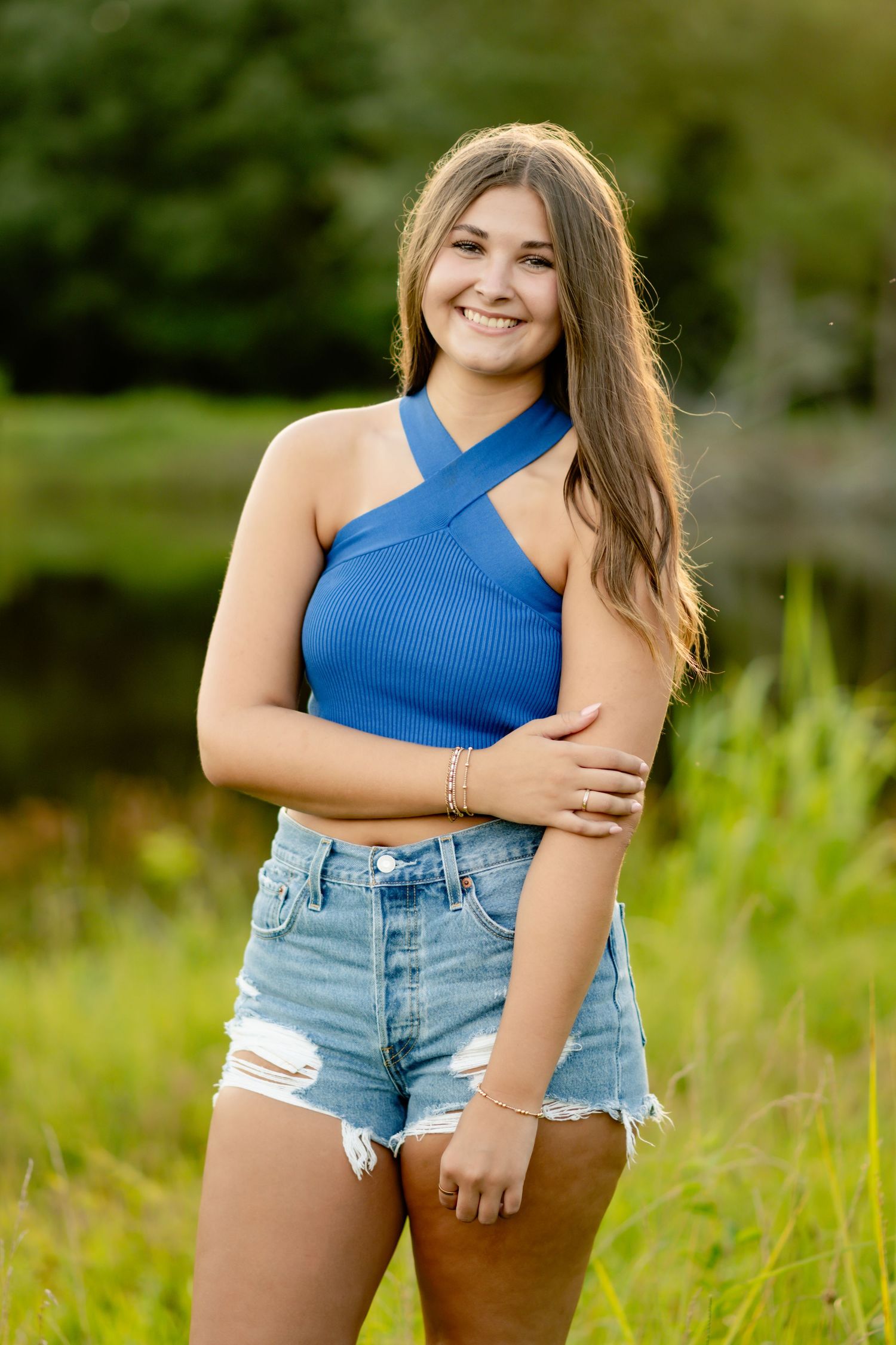 Summer portrait in a blue halter top and denim shorts against a natural background.