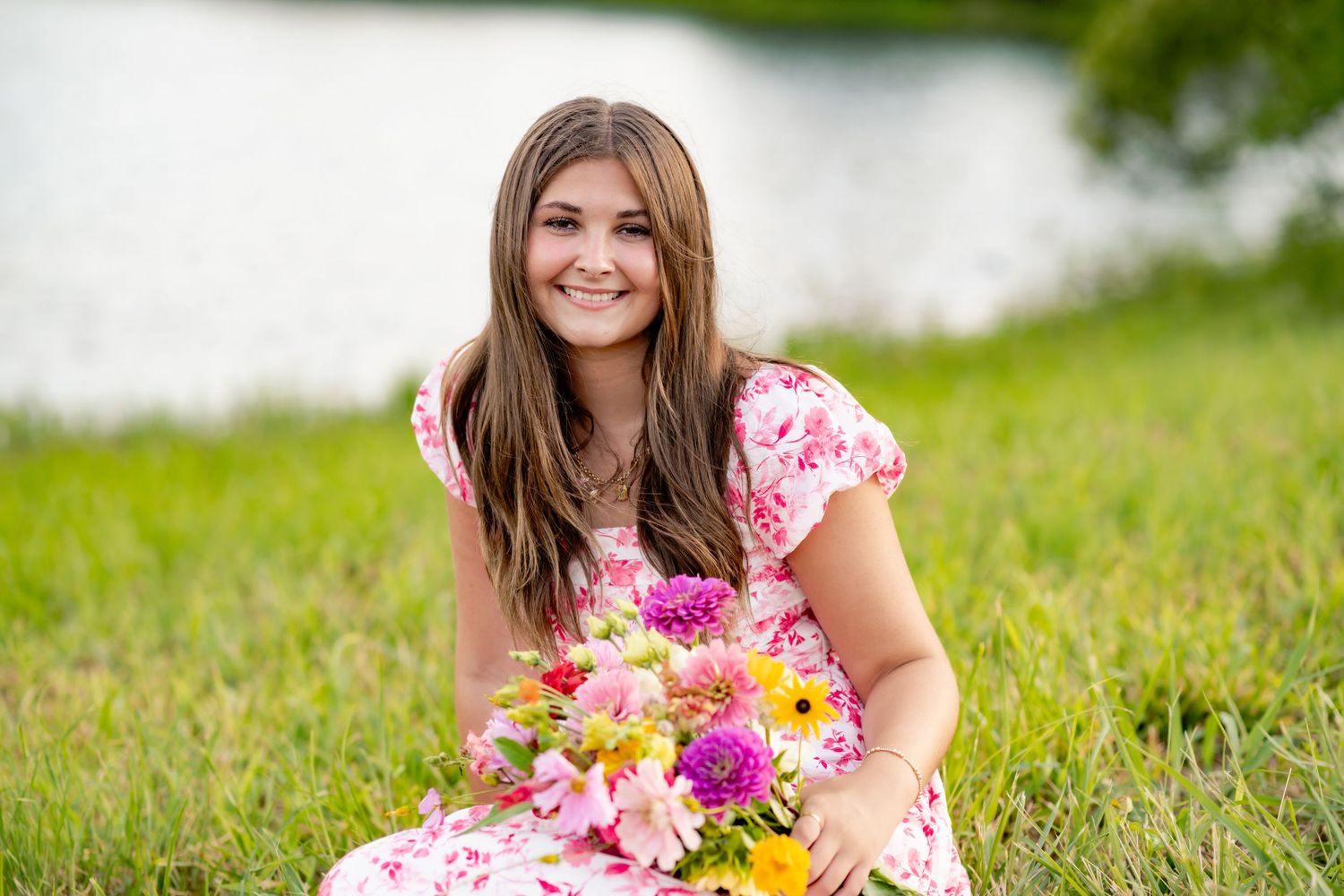 A person lying in a grassy field with pink and yellow flowers on a sunny summer day.