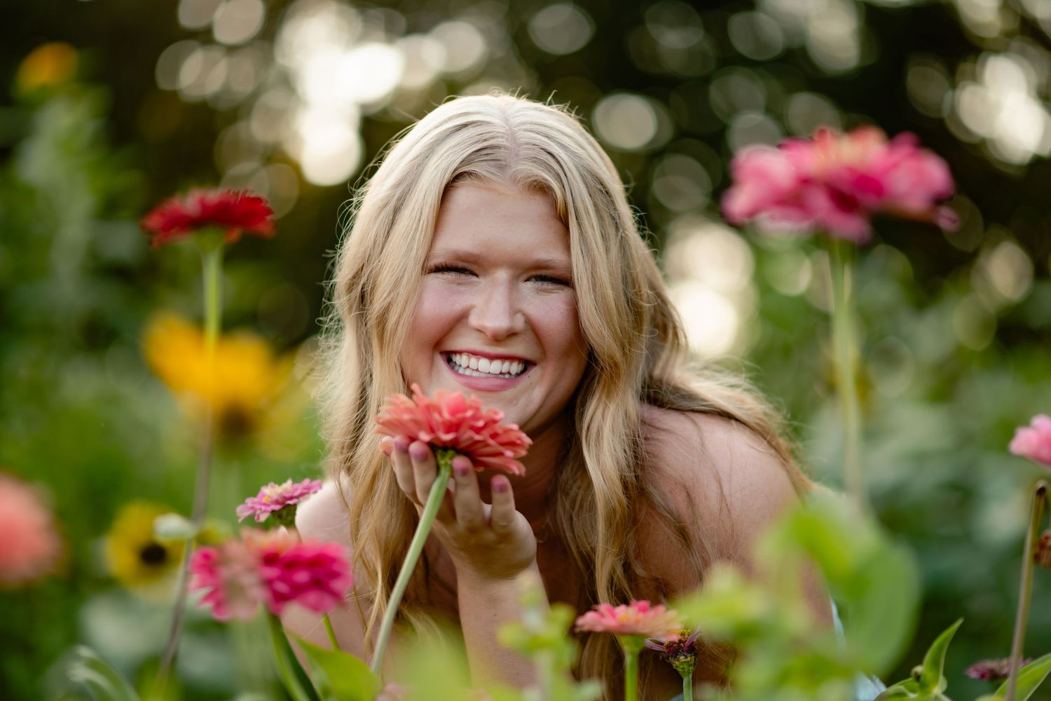 Someone enjoys candid moments in a vibrant garden filled with colorful summer flowers and natural bokeh lighting effects.