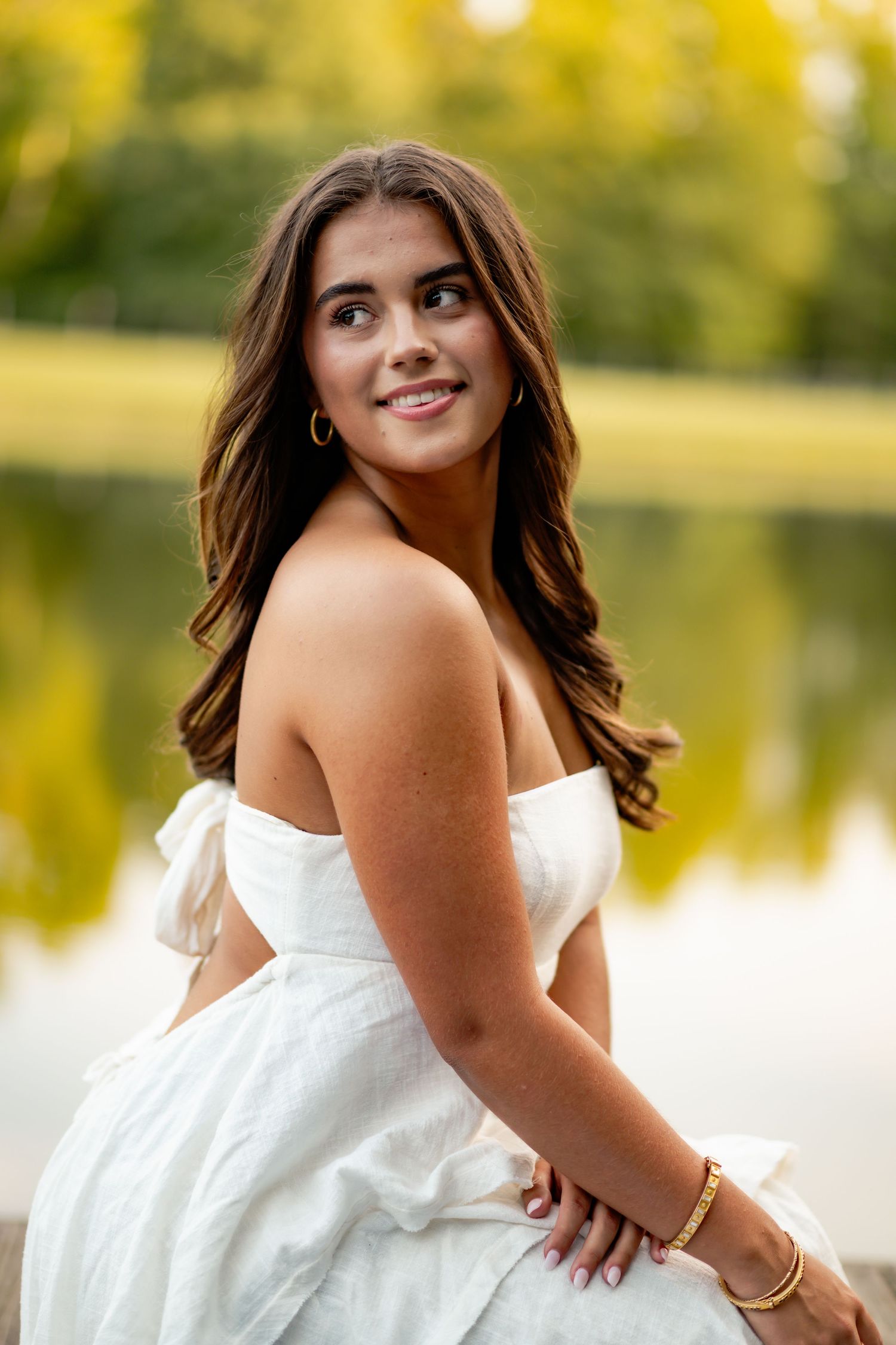 Elegant portrait series in a white summer dress by a lake during golden hour.