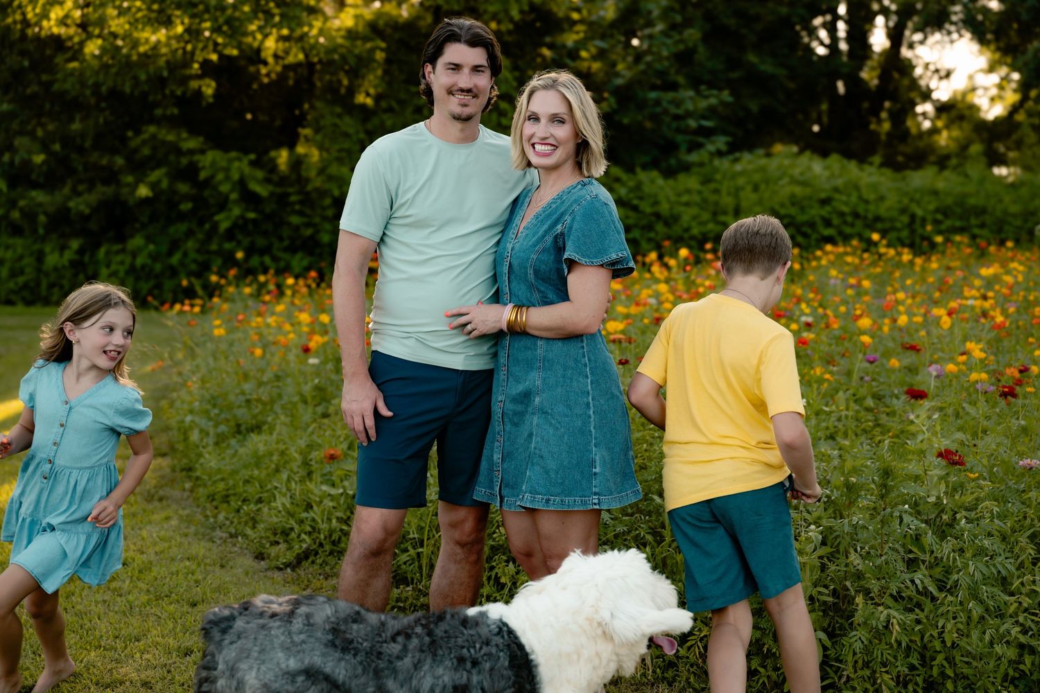 Candid family portrait in field of wildflowers during golden hour.