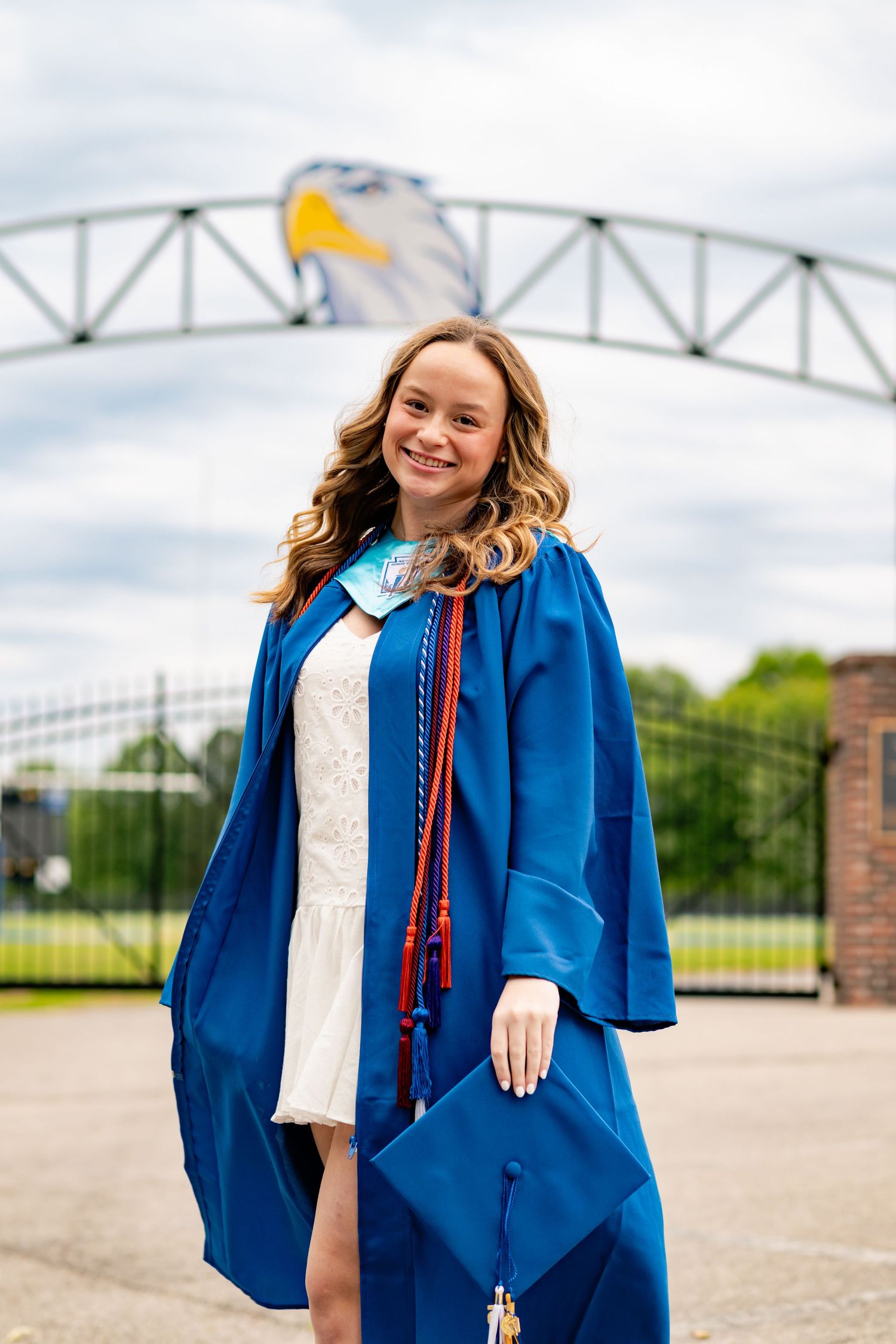 Graduation photos in a bright blue cap and gown against an outdoor backdrop.