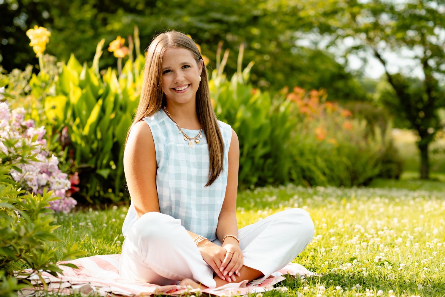 Casual outdoor portrait on a blanket surrounded by blooming flowers in a garden setting.
