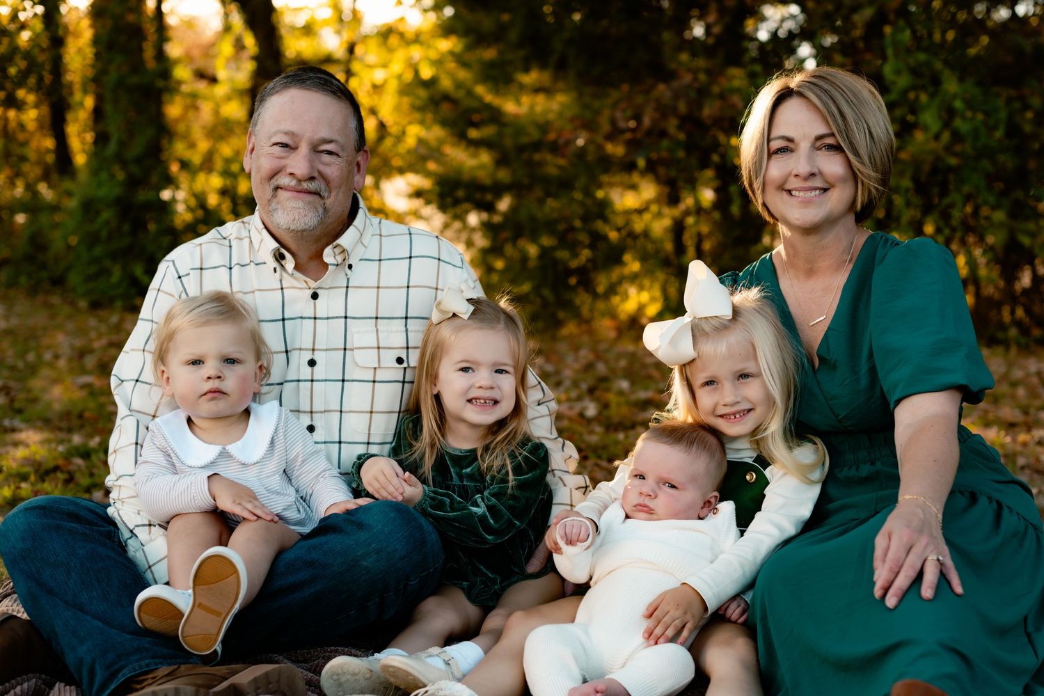 A family of five poses together for a portrait outdoors during golden hour with beautiful autumn lighting.