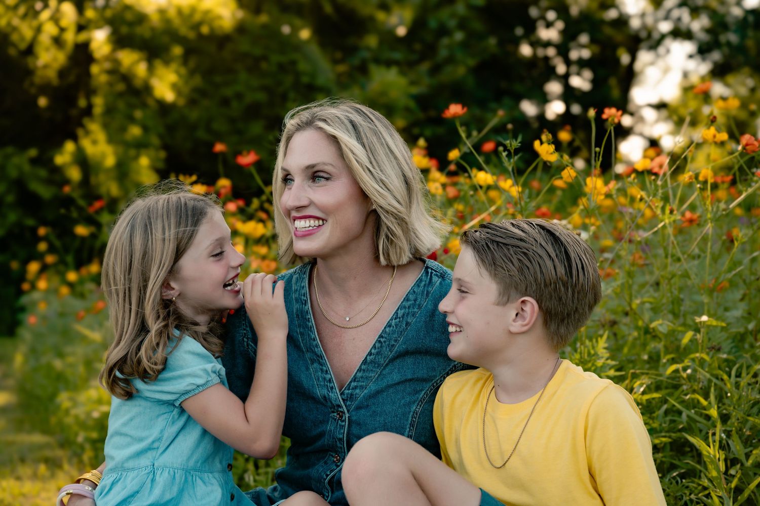 Family shares joyful moment together in blooming wildflower field at sunset.