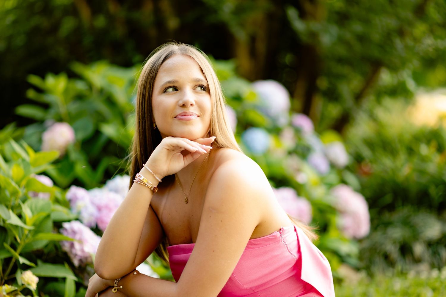 Dreamy outdoor portrait pose among purple hydrangea flowers.