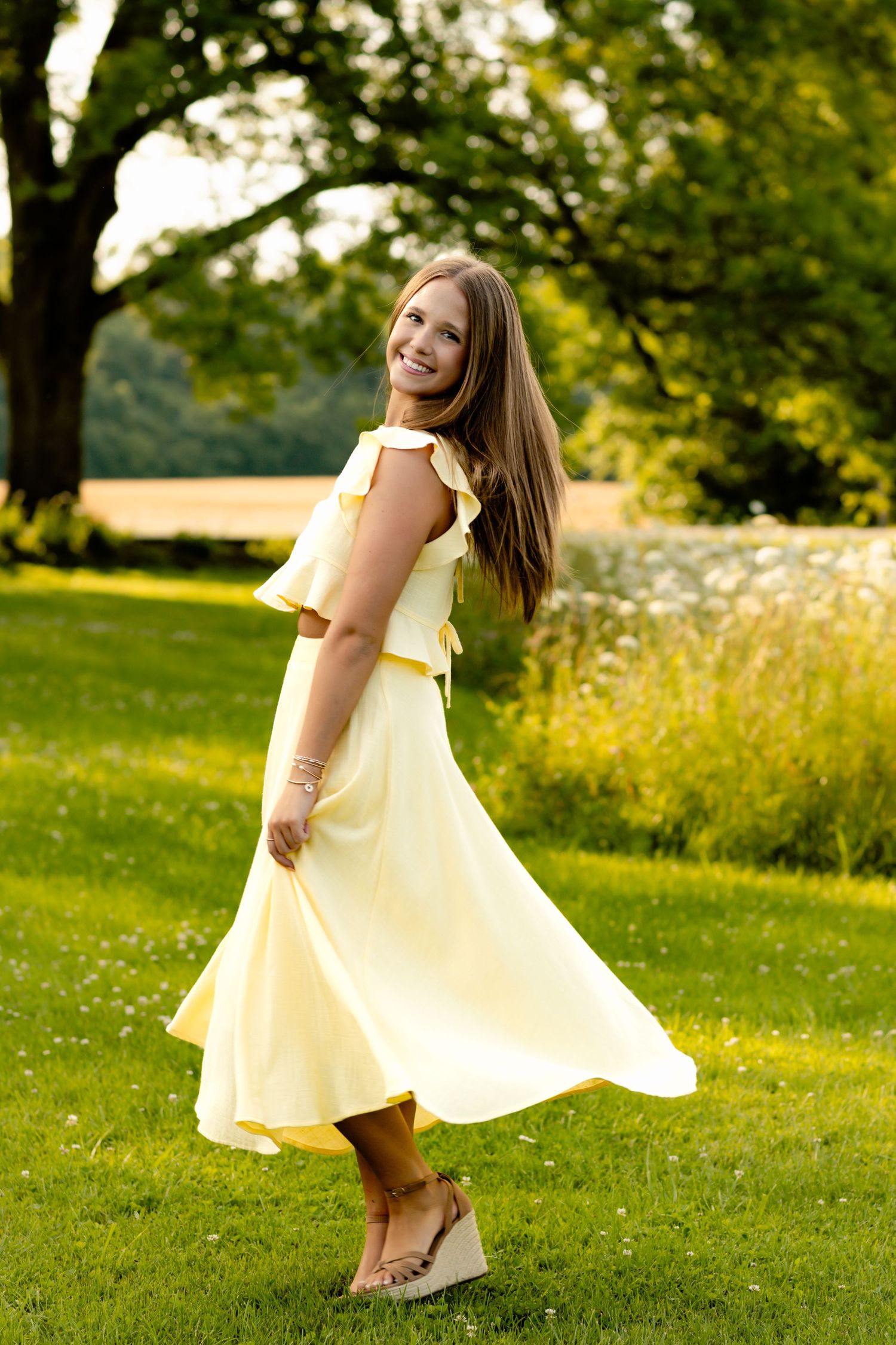 Twirling motion shot in a flowing yellow summer dress on a grassy lawn.