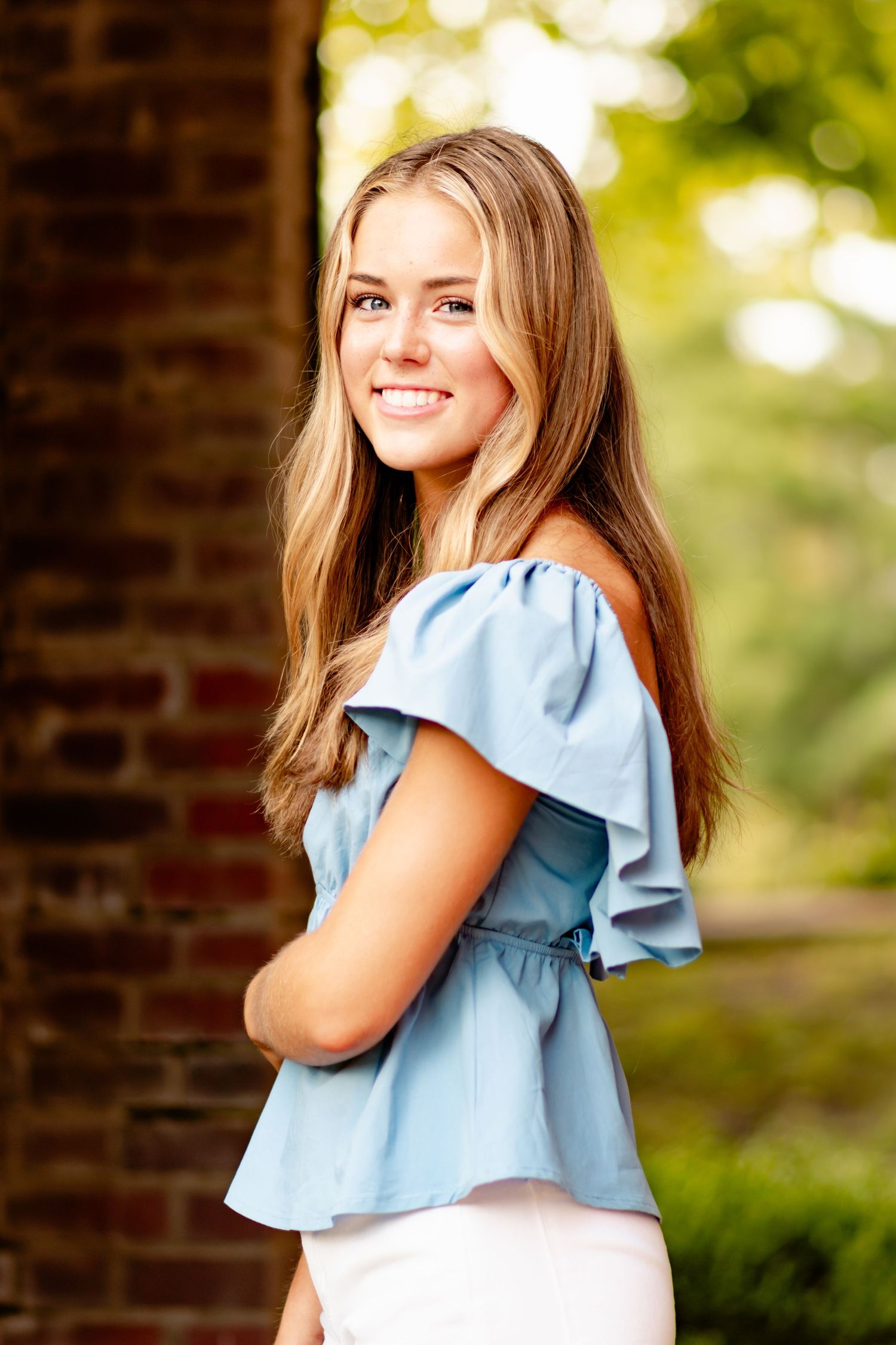 Portrait sequence of person wearing light blue ruffled top posing outdoors with blurred natural background.