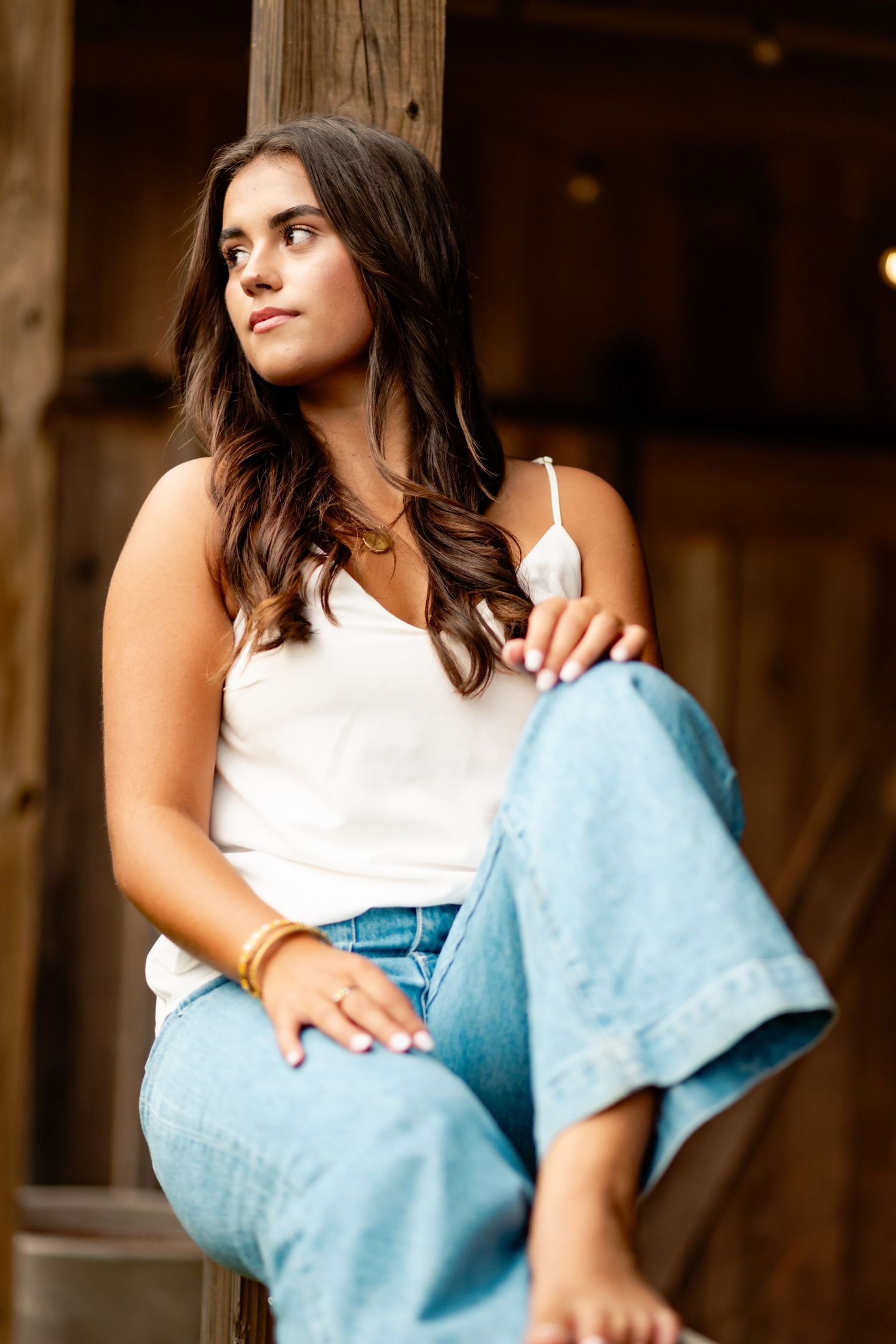 Casual portrait session in white top and denim against rustic wooden backdrop.