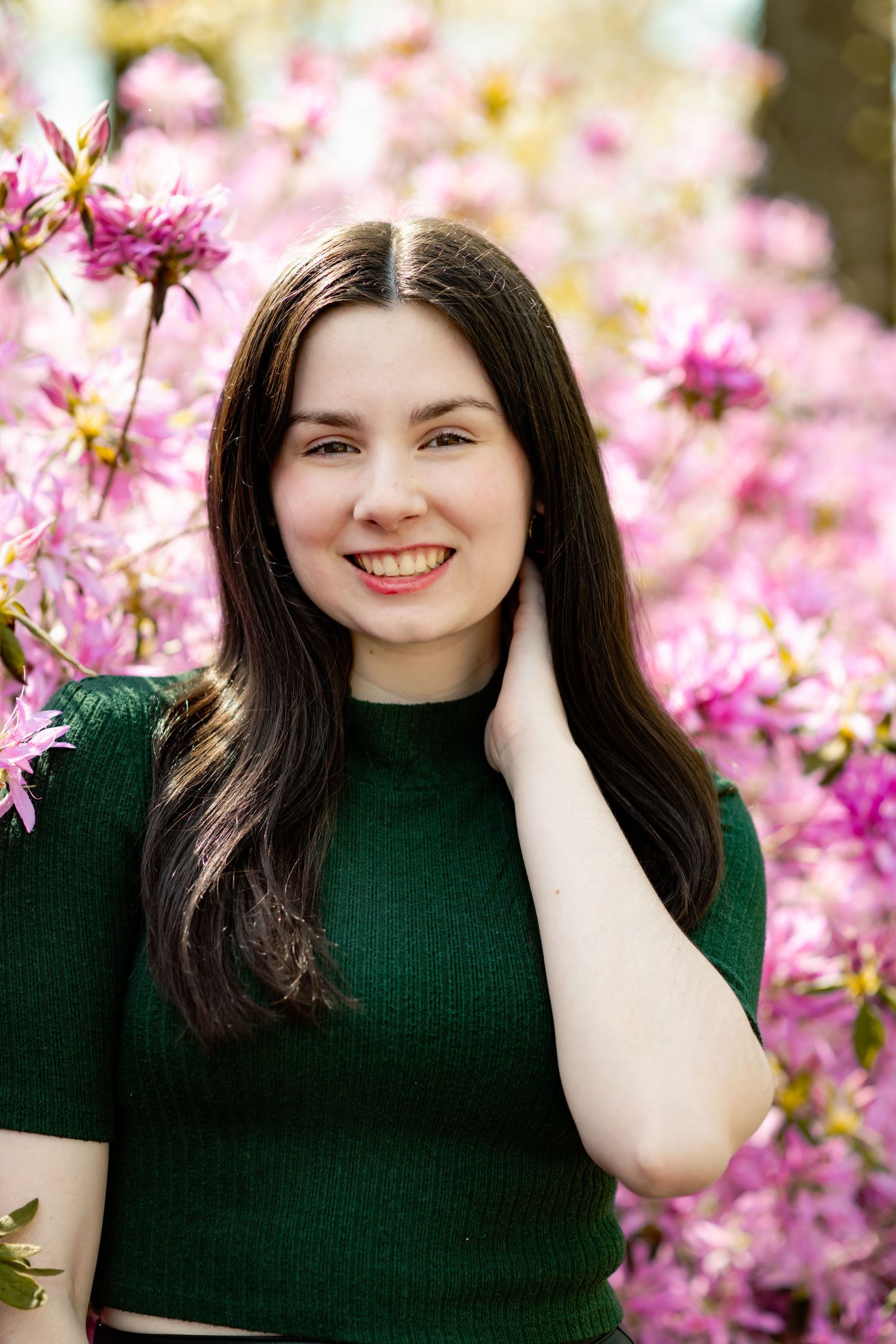 A person in a dark green top poses against vibrant pink spring blossoms in a series of outdoor portrait shots.