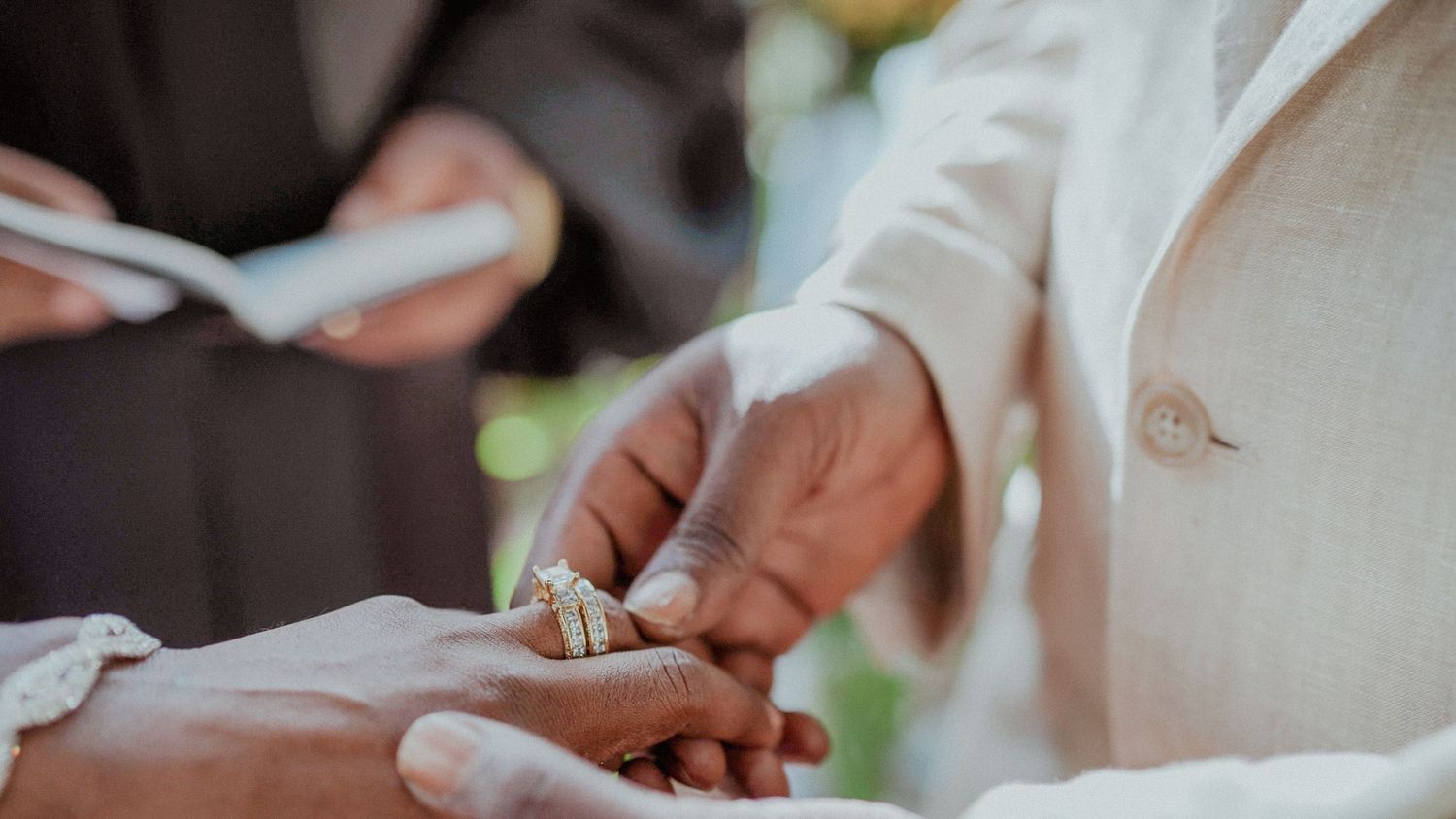 Close up shot of hands exchanging rings during an elegant wedding ceremony.