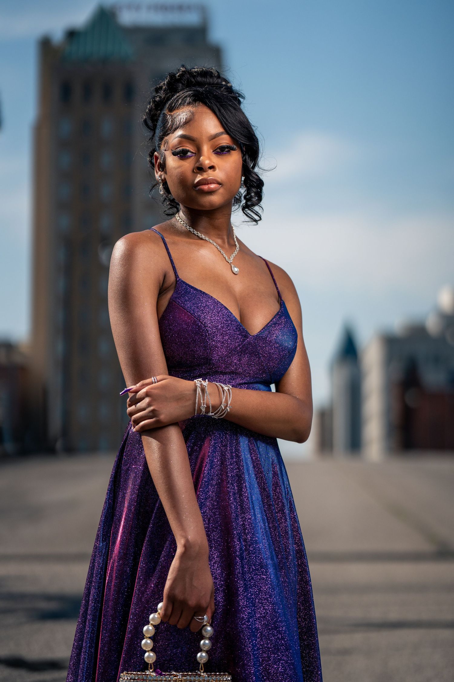 Elegant purple glitter gown worn with matching accessories and jewelry.