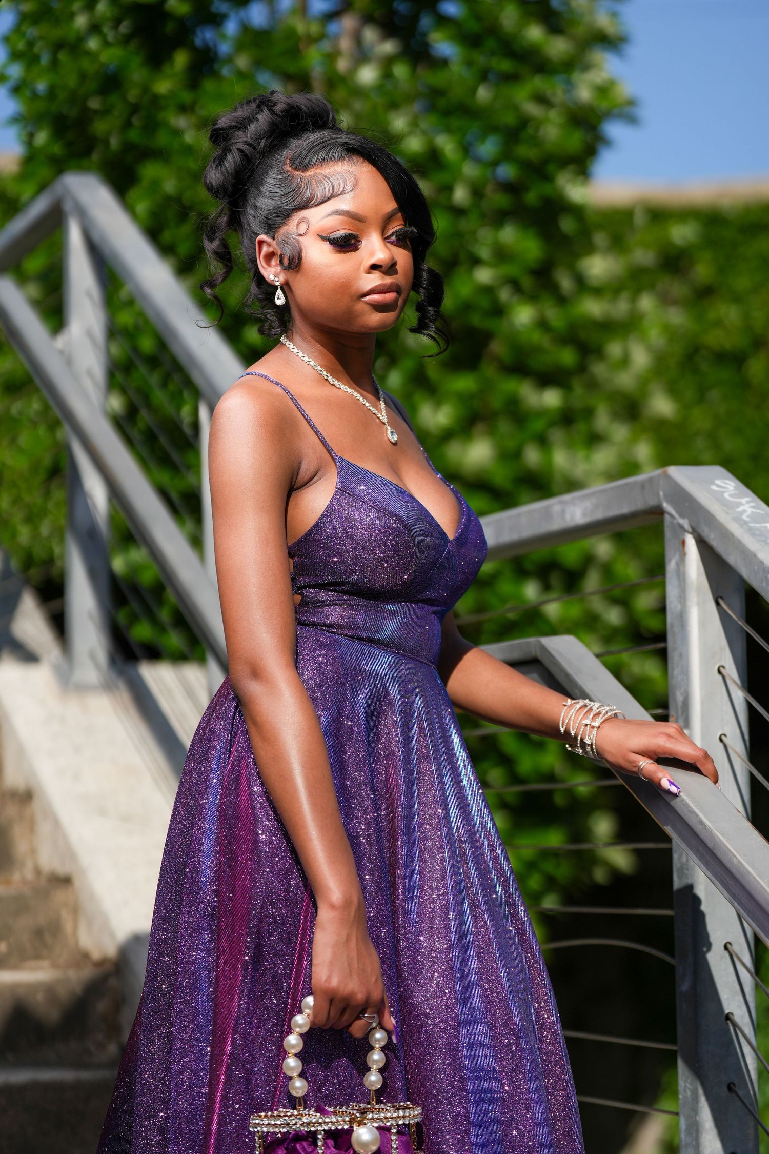 Elegant purple prom dress photographed on outdoor staircase.