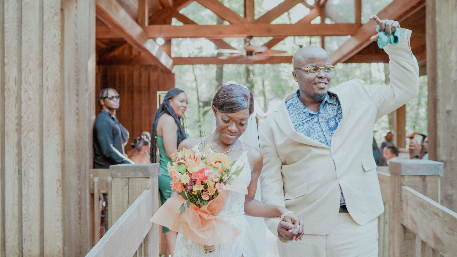 Wedding party celebrates in rustic barn venue with romantic string lights and vintage wood beam details.