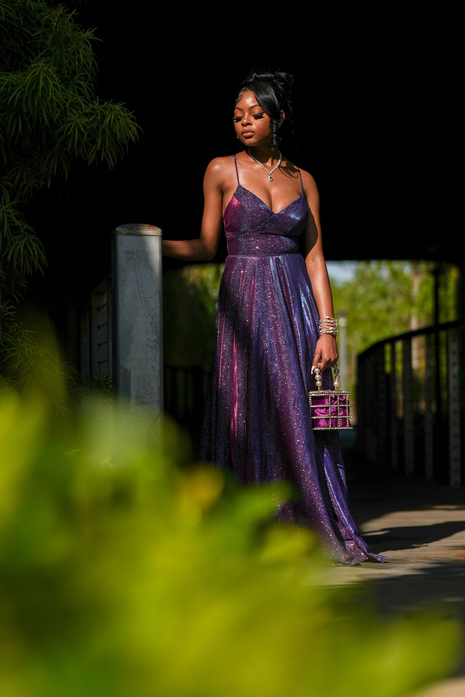 Shimmering purple gown photographed in garden setting with greenery.