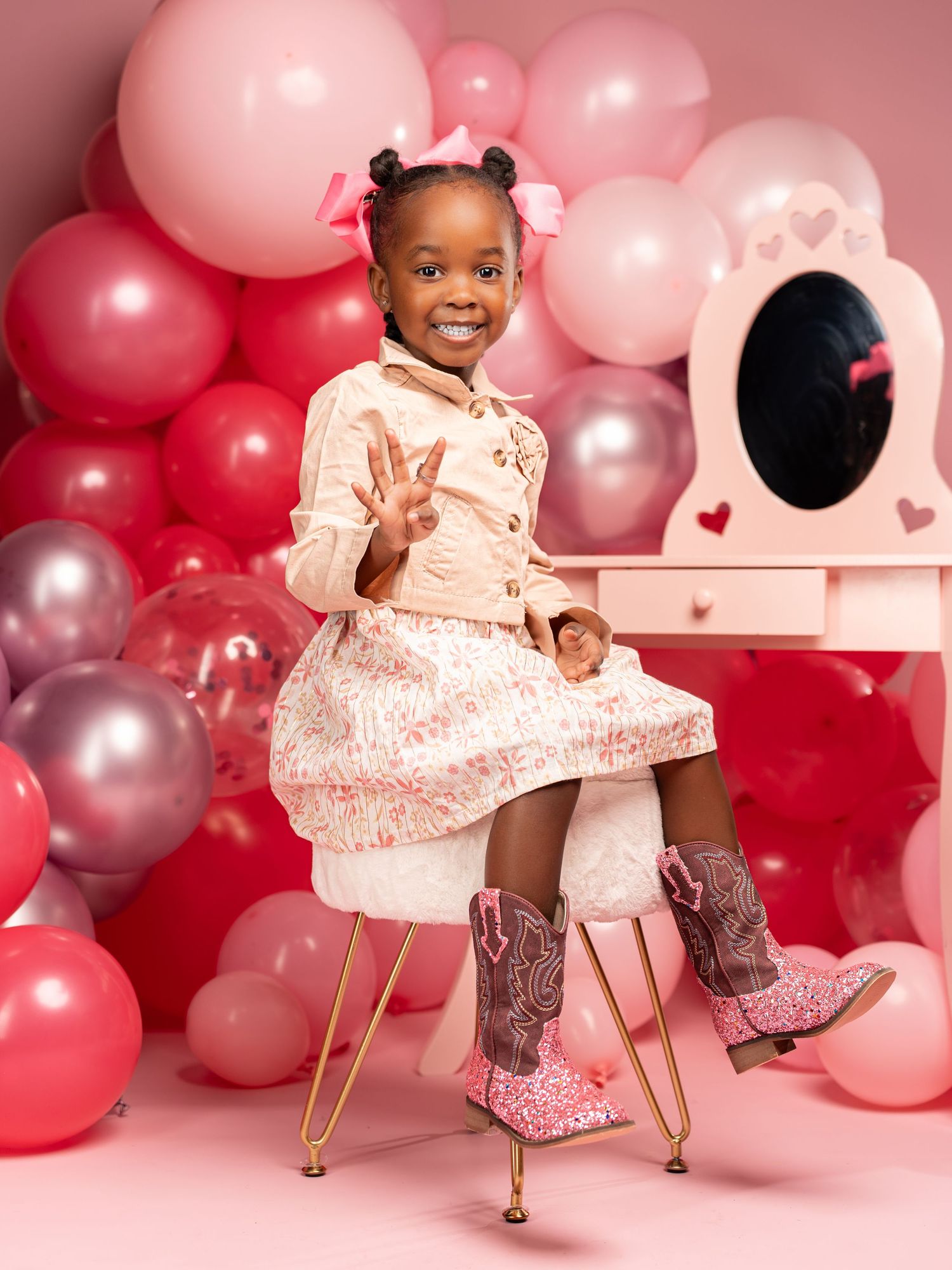 Pink and gray balloon backdrop creates a festive setting for a Valentine's Day themed photoshoot with playful poses.